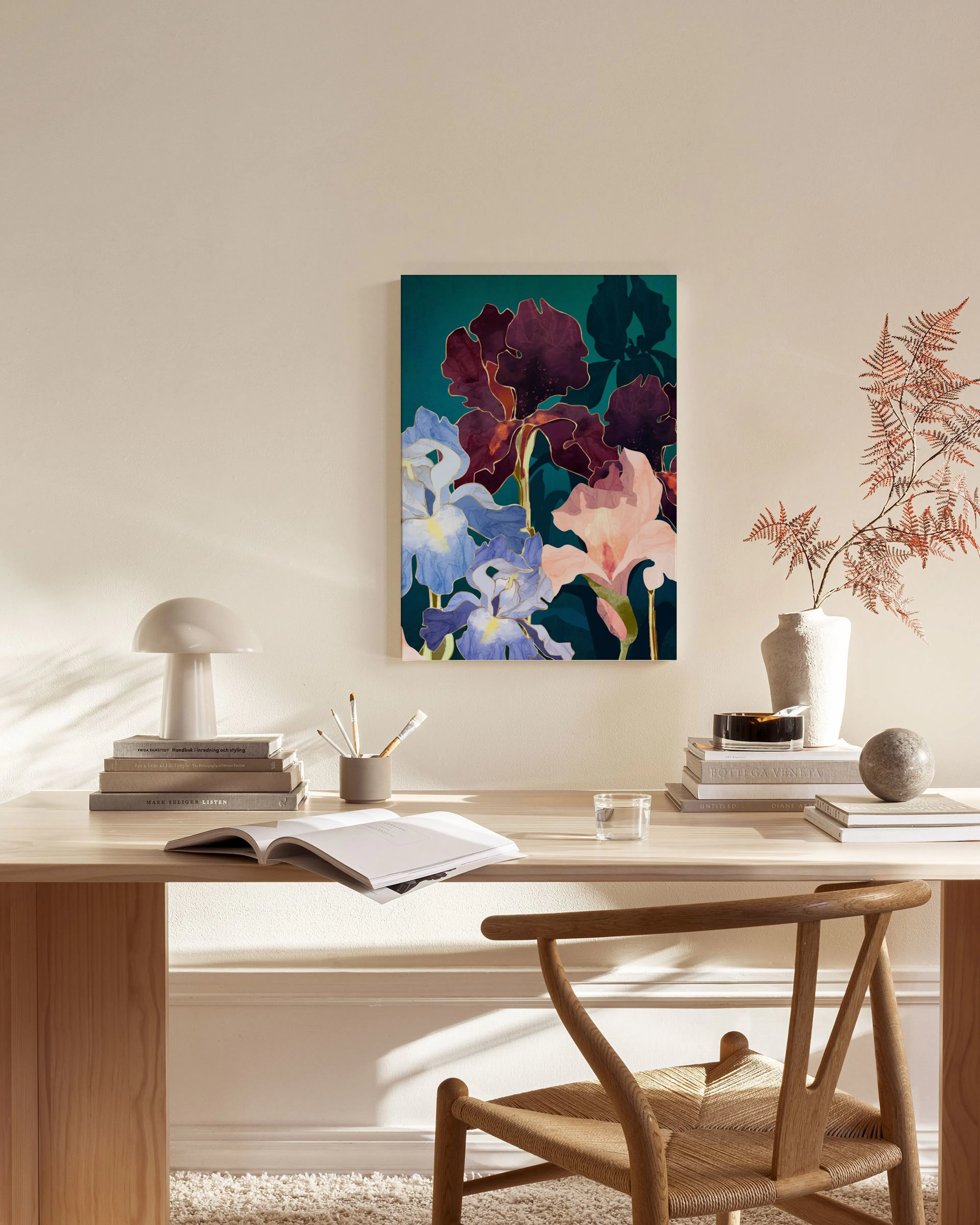 A colorful iris floral print with dark red, pale pink, and blue flowers, hanging above a wooden console table in a living room.