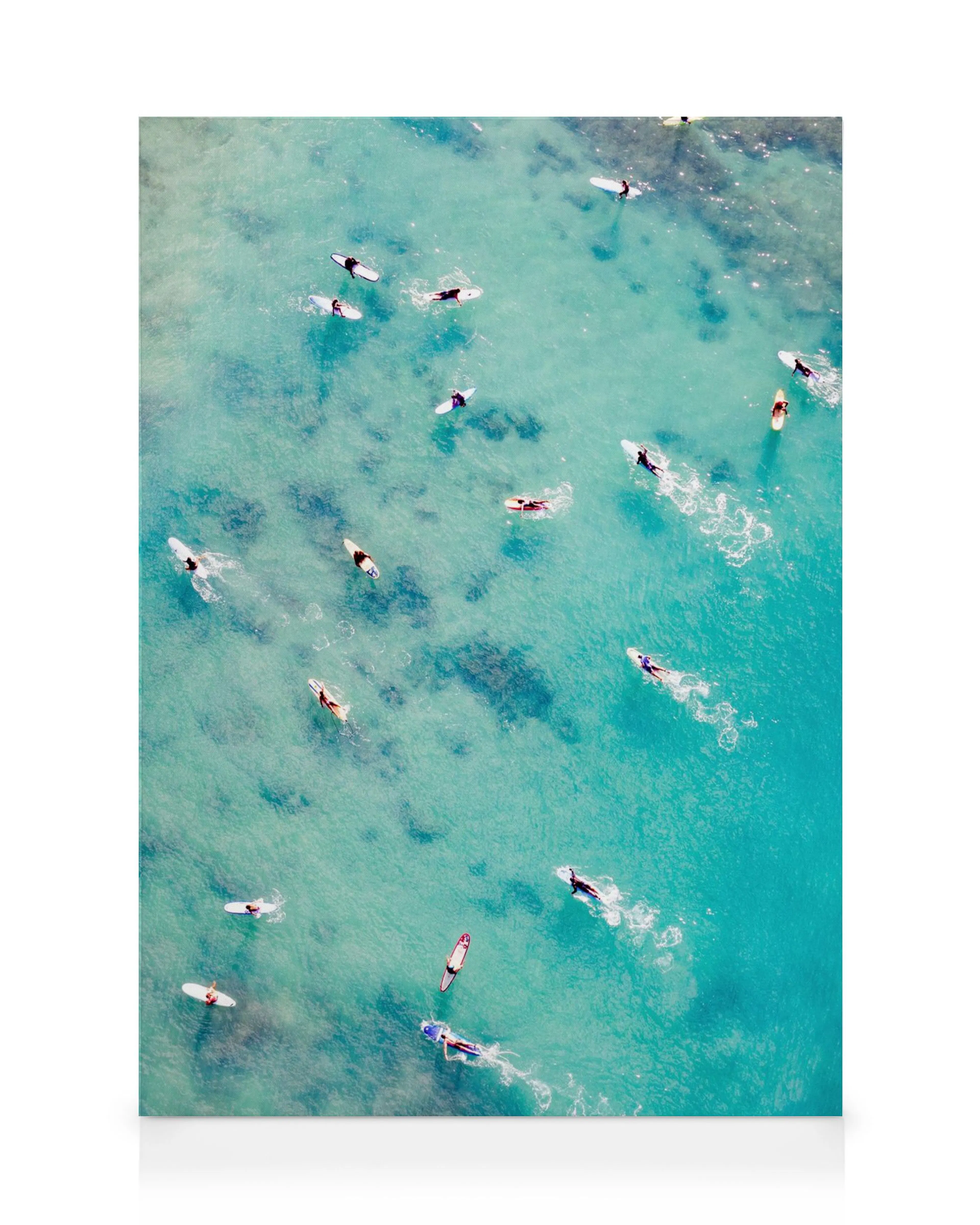 Leinwandbild mit einer Luftaufnahme von Surfern und ihren Surfbrettern auf türkisblauem Wasser.