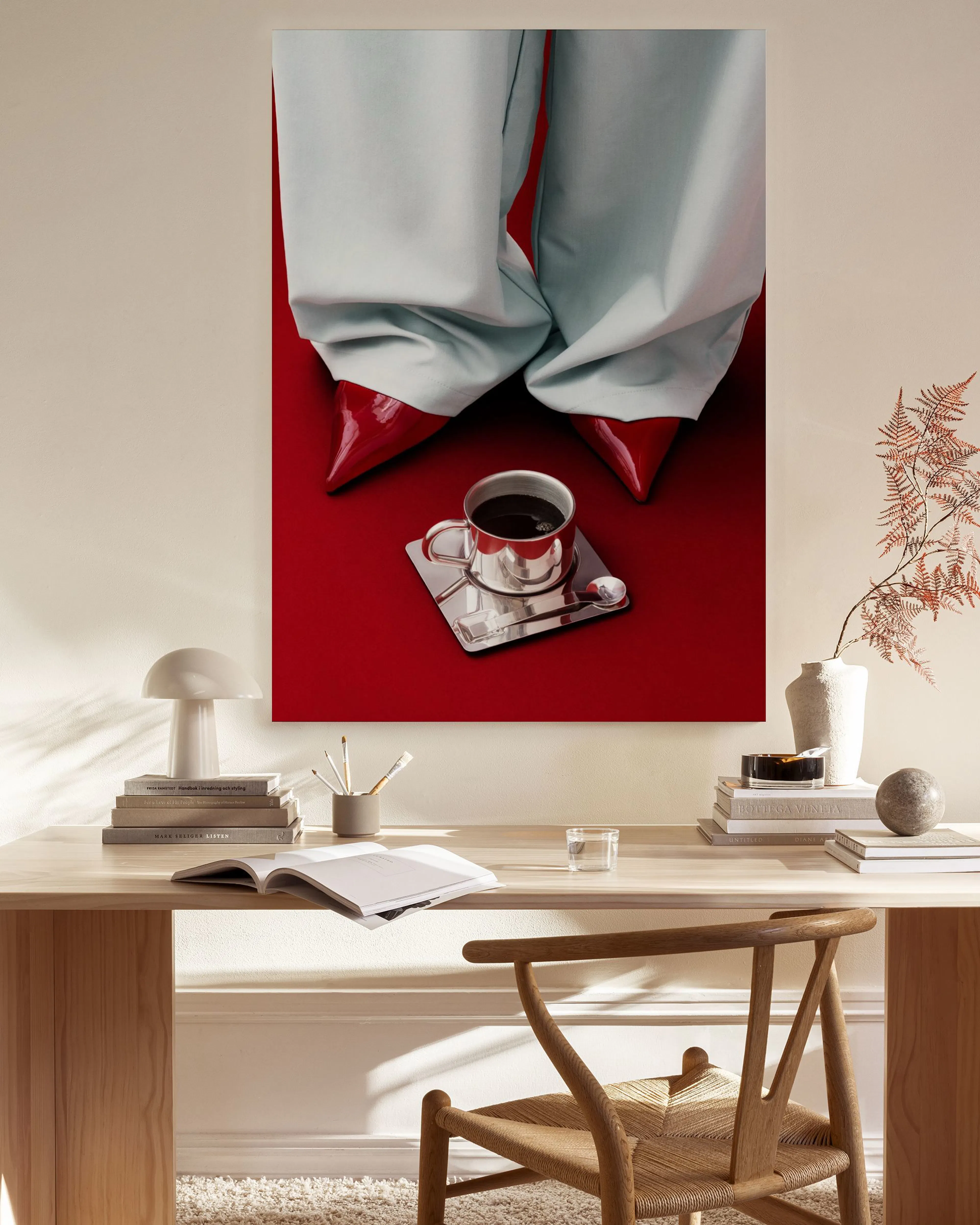 A canvas print of a person in light blue pants and red heels, with a coffee cup on a tray, displayed in a bright living room.