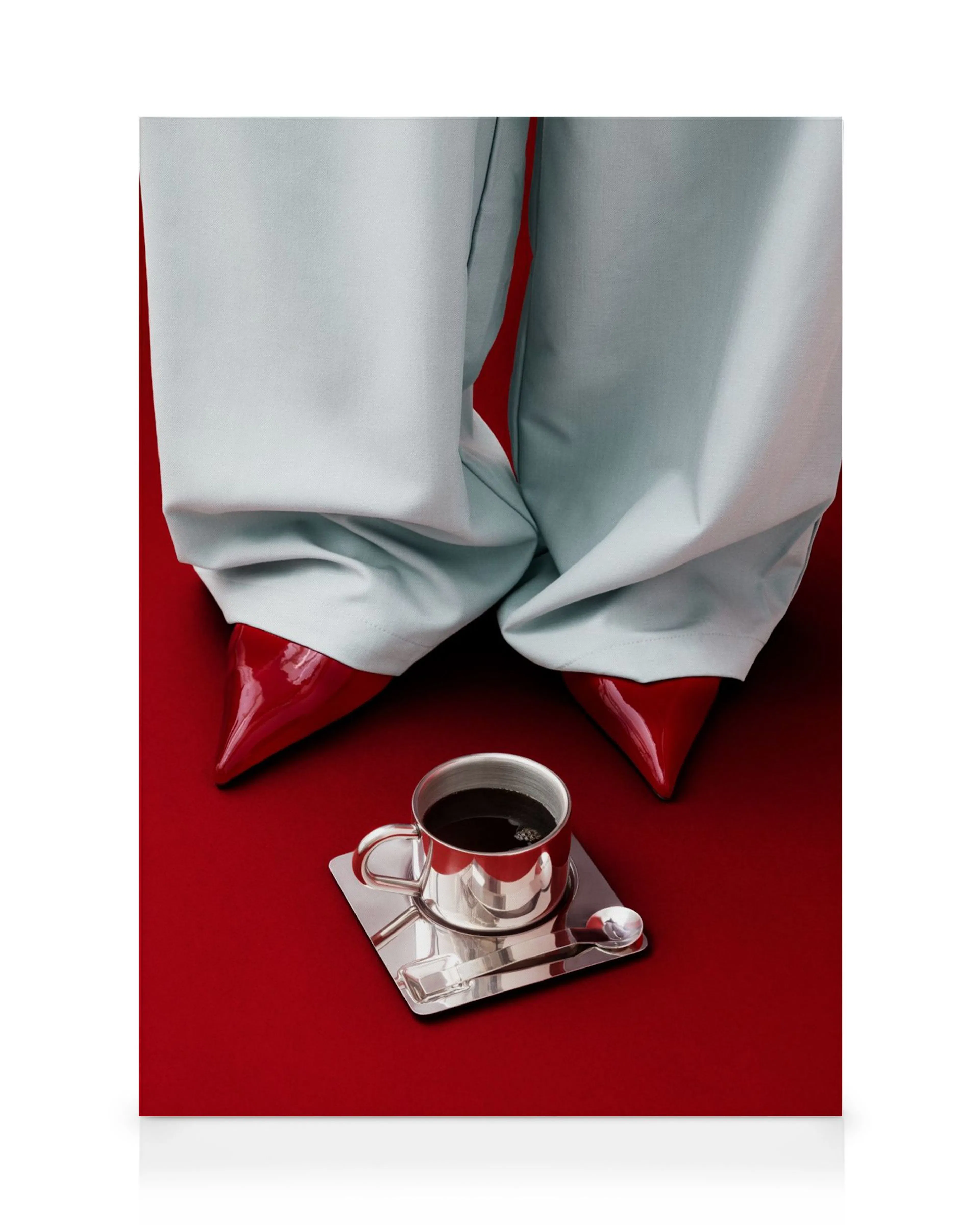A canvas print featuring pale blue trousers and red pointed shoes, with a silver coffee cup on a red background.