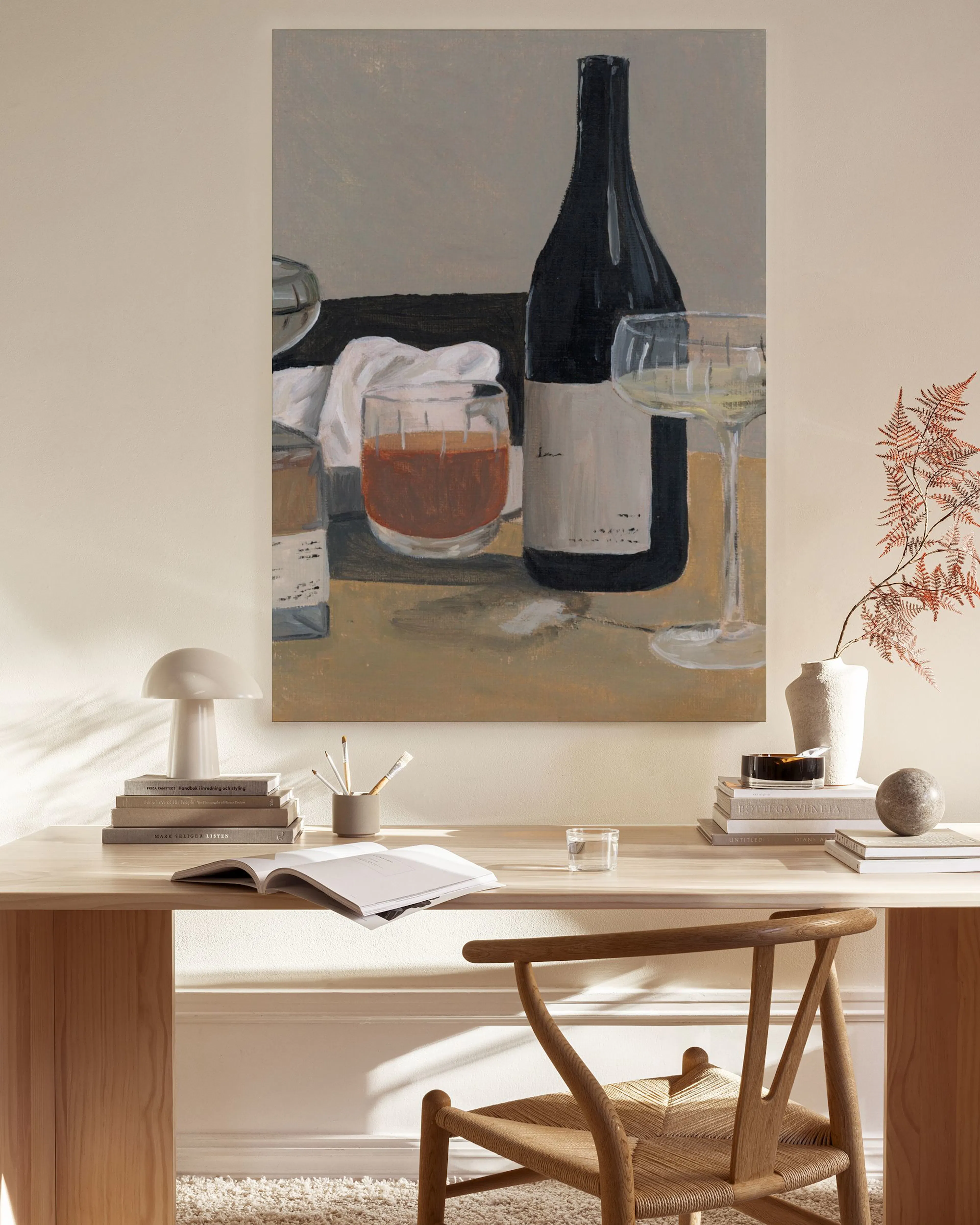 Een canvas met een stilleven van een fles wijn en twee glazen, hangend in een neutrale woonkamer boven een dressoir.