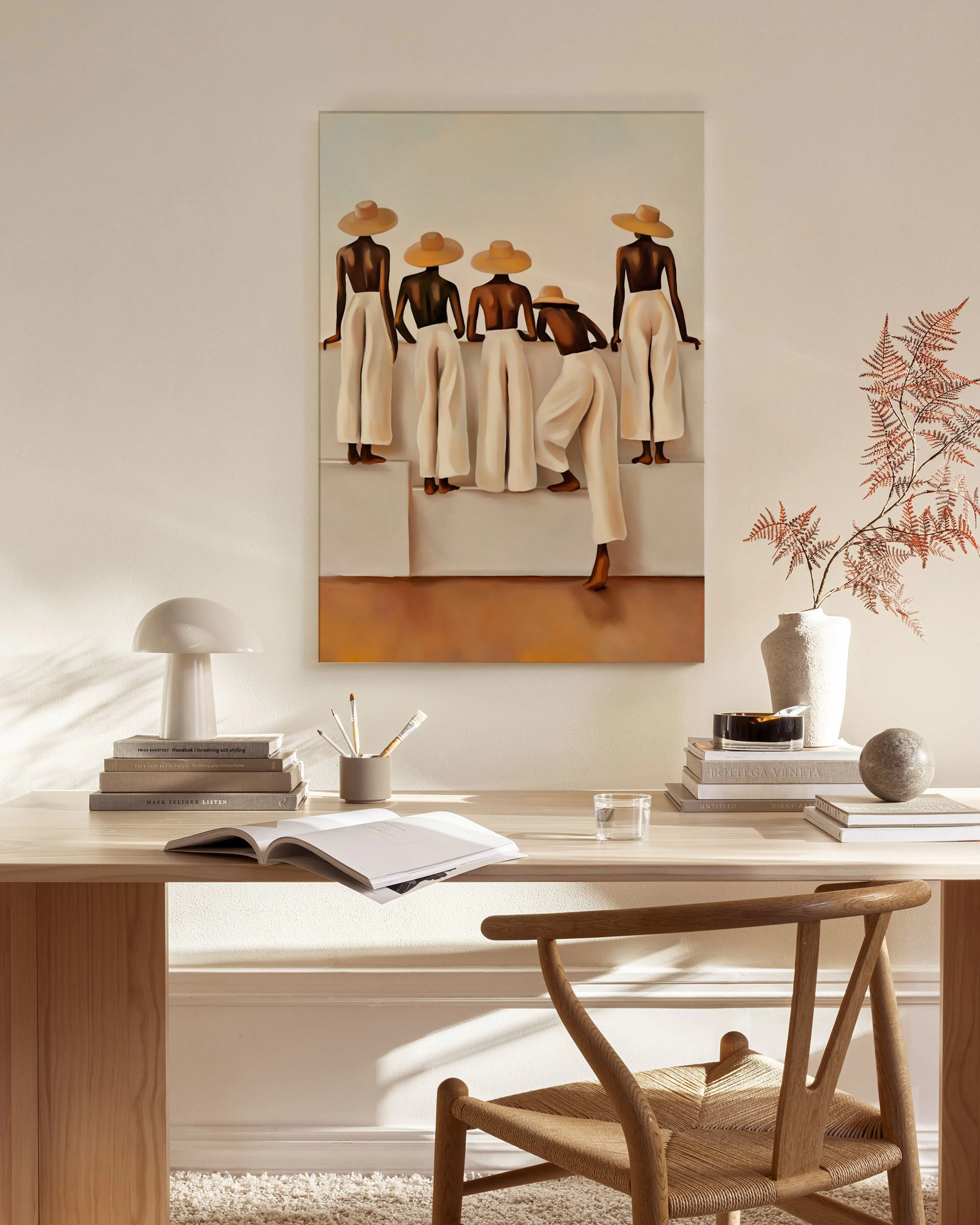 A canvas print of five figures in straw hats and white pants, hanging in a minimalist living room.