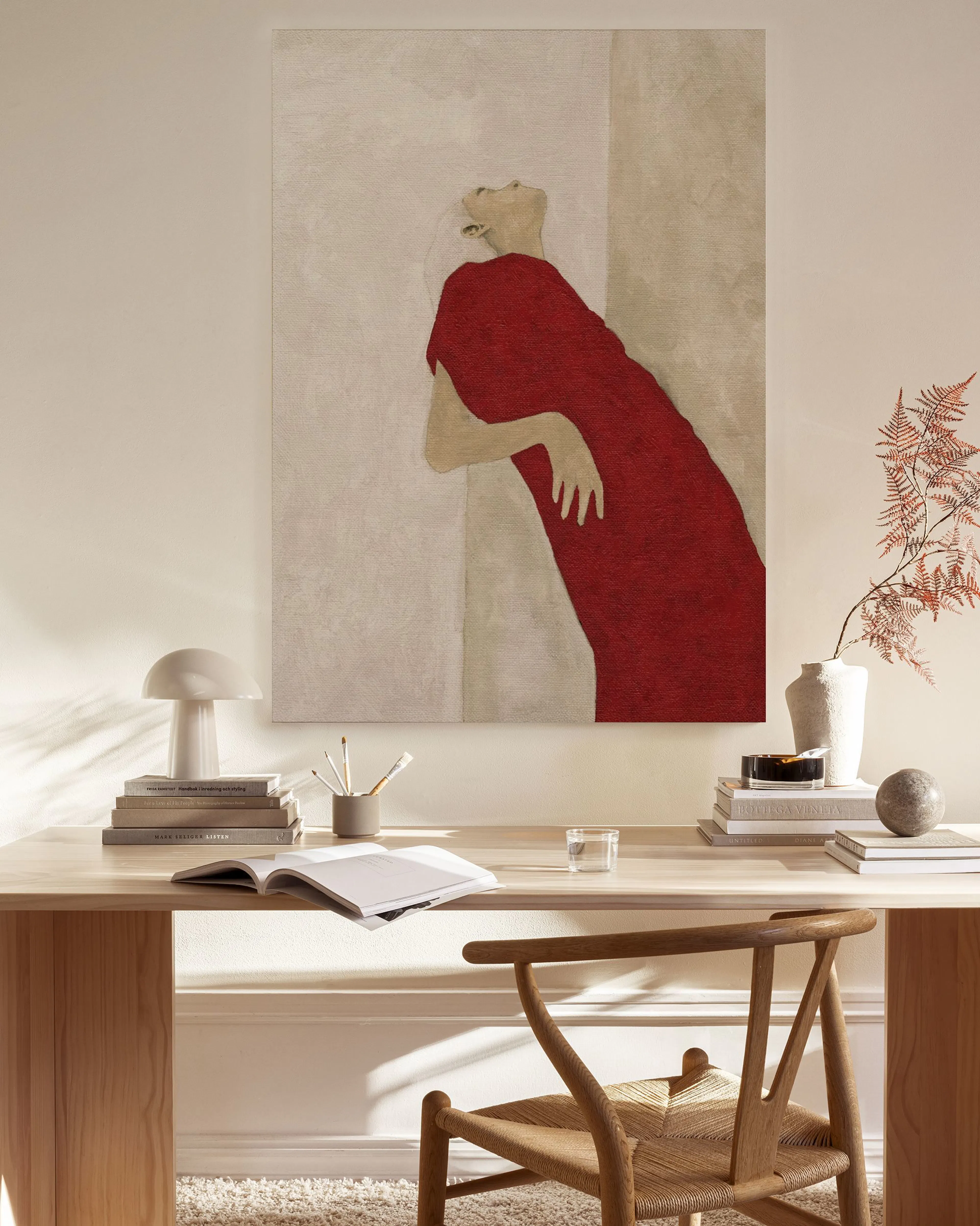 Lienzo de una figura en vestido rojo recostada, con el rostro hacia arriba, colgado en una sala de estar moderna.