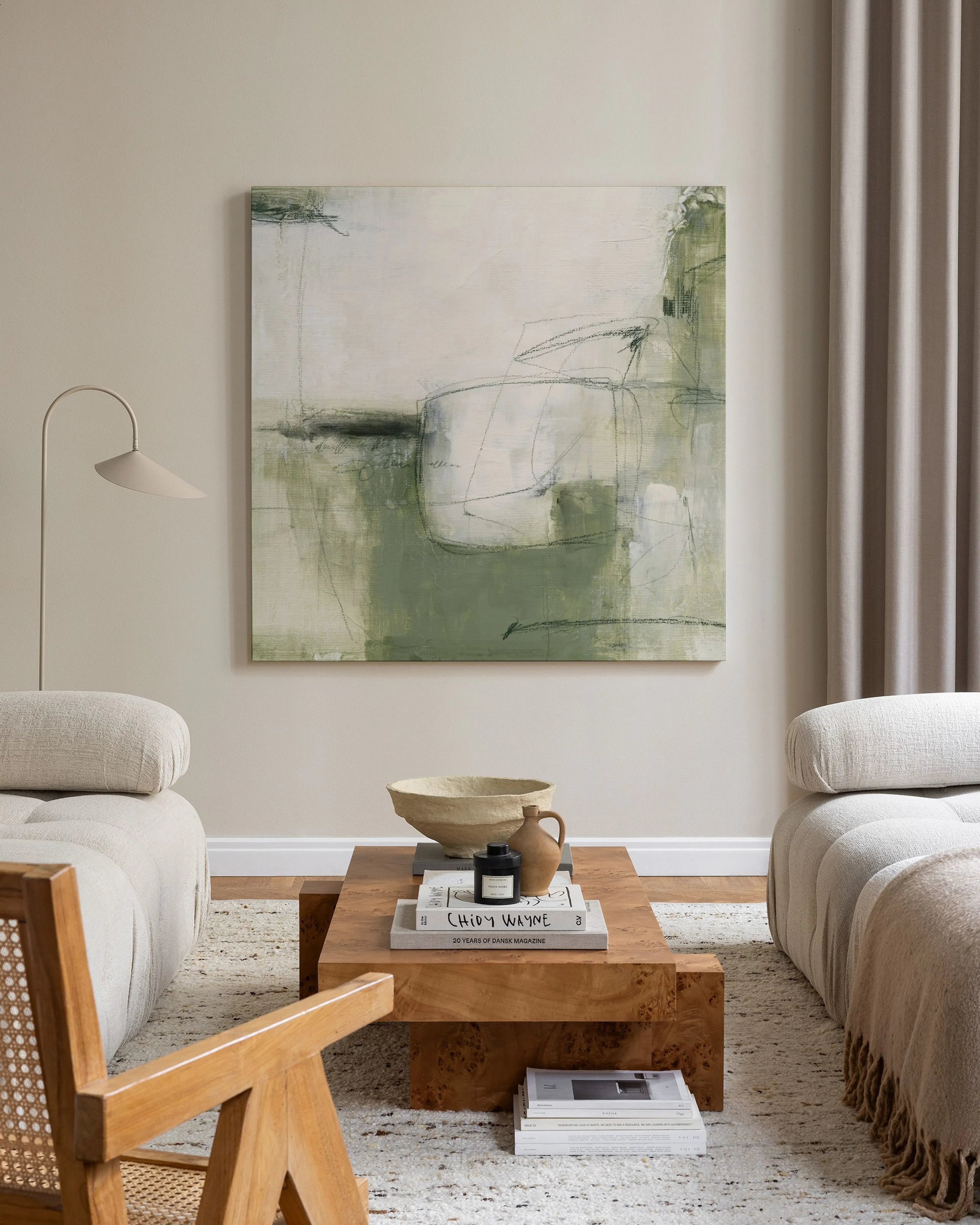 Tela decorativa abstrata em tons de verde e branco, com formas orgânicas, pendurada numa sala de estar minimalista.