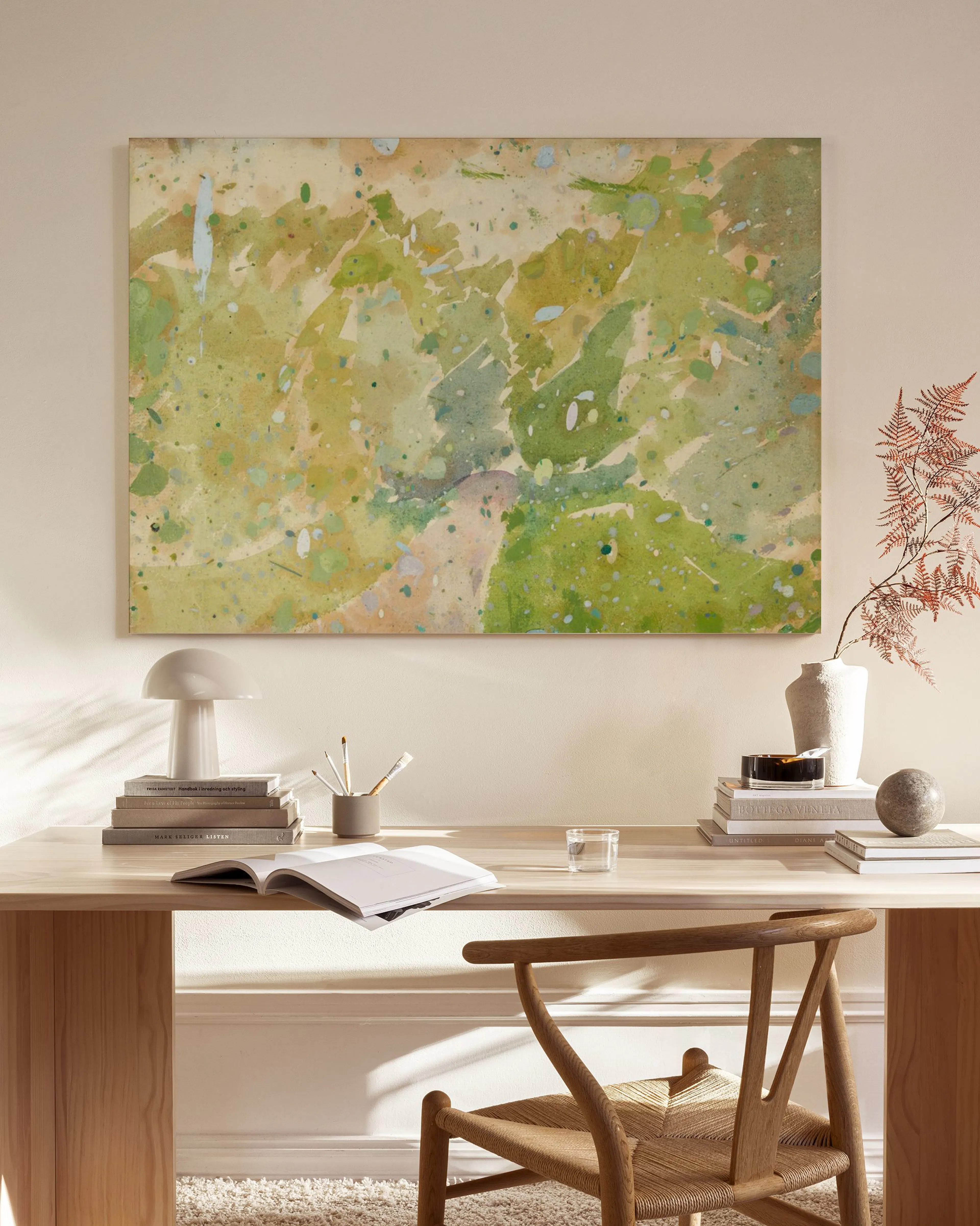 Abstract canvas print with green, yellow, and beige splotches, hanging in a minimalist living room.