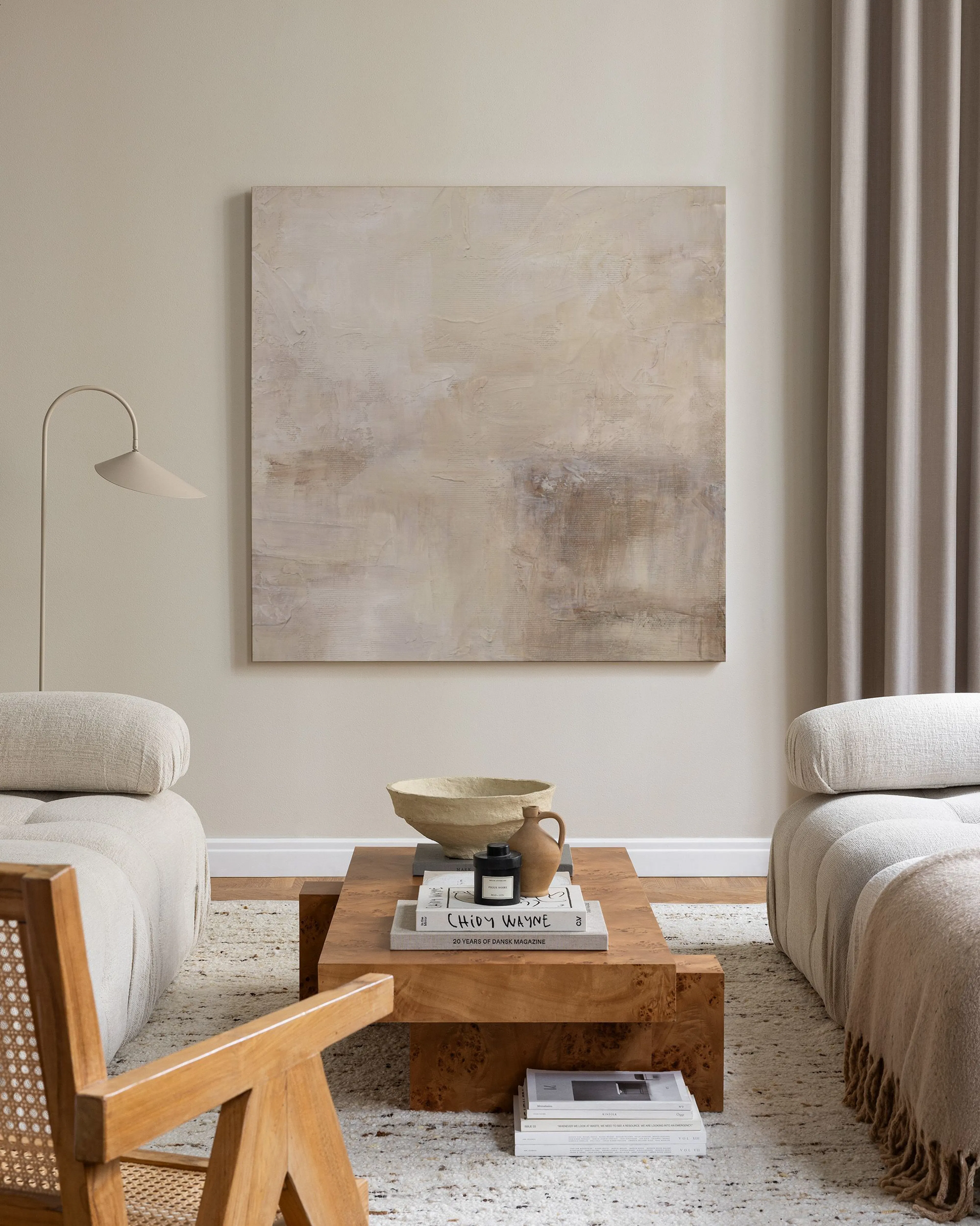 Abstract canvas print with muted beige, brown, and white tones, hanging above a console table in a minimalist living room.