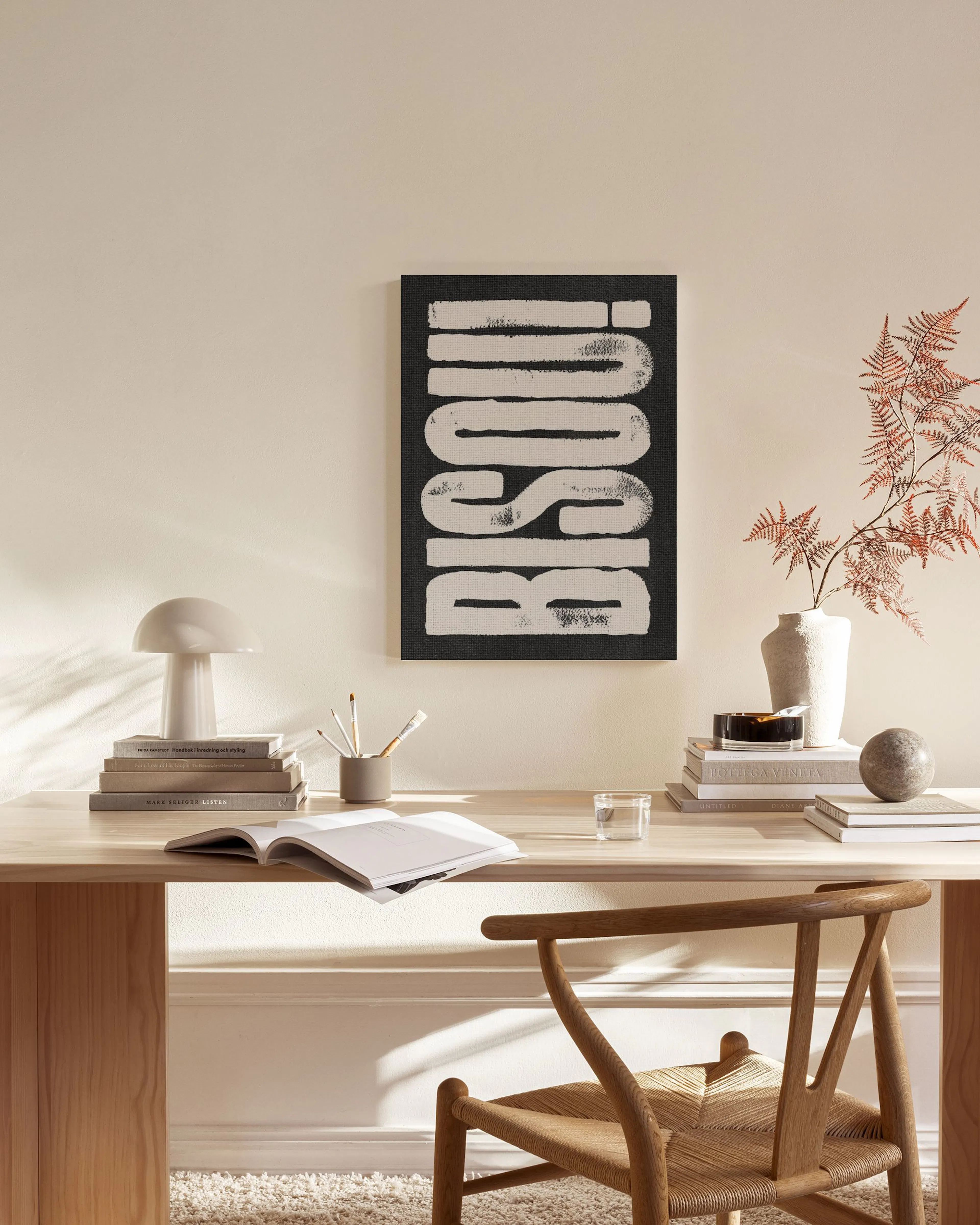 Lienzo blanco y negro con la palabra Bisou! en un interior minimalista con muebles de madera.