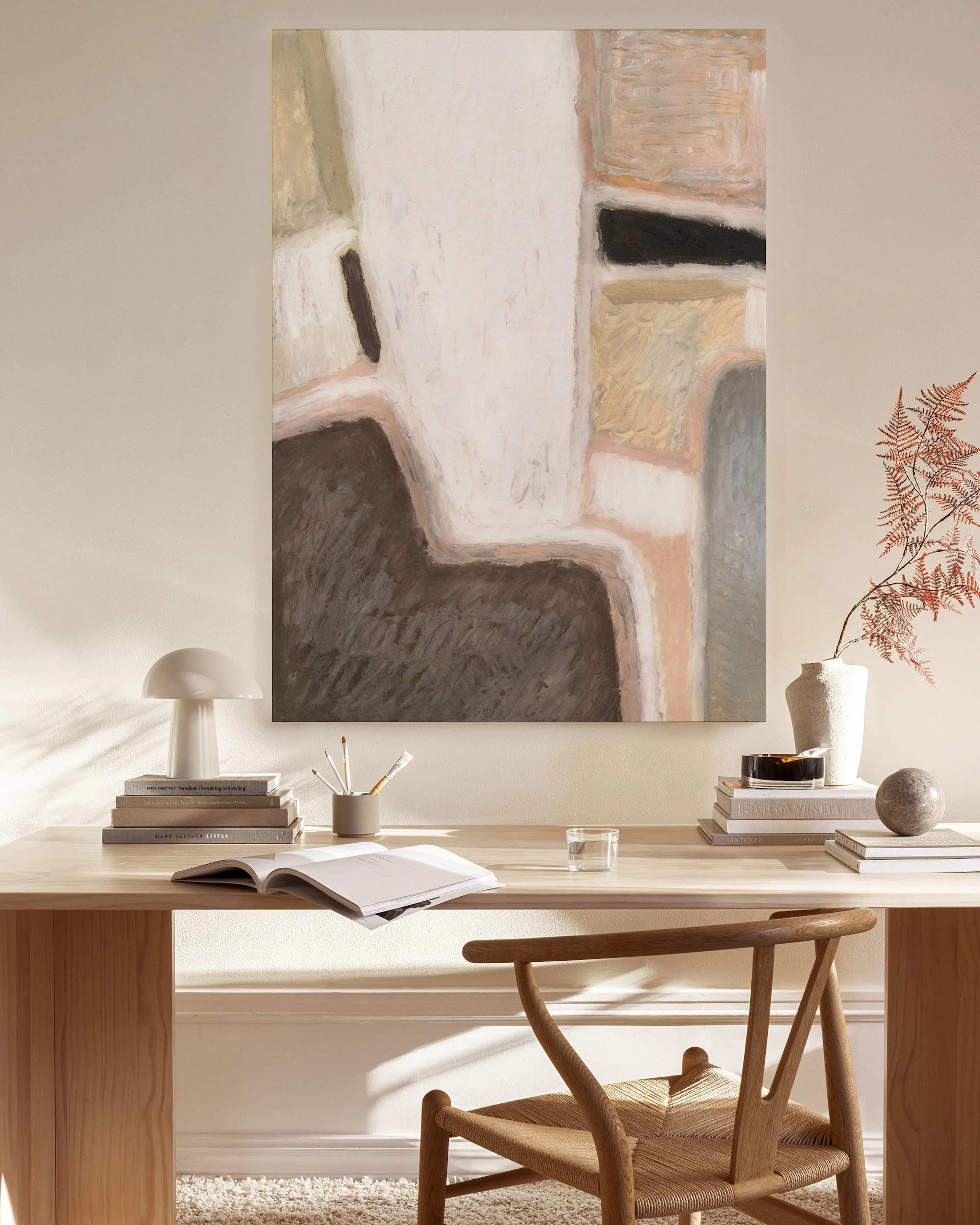 Leinwandbild mit organischen Formen in Beige, Braun und Weiß, das in einem hellen Wohnzimmer hängt.
