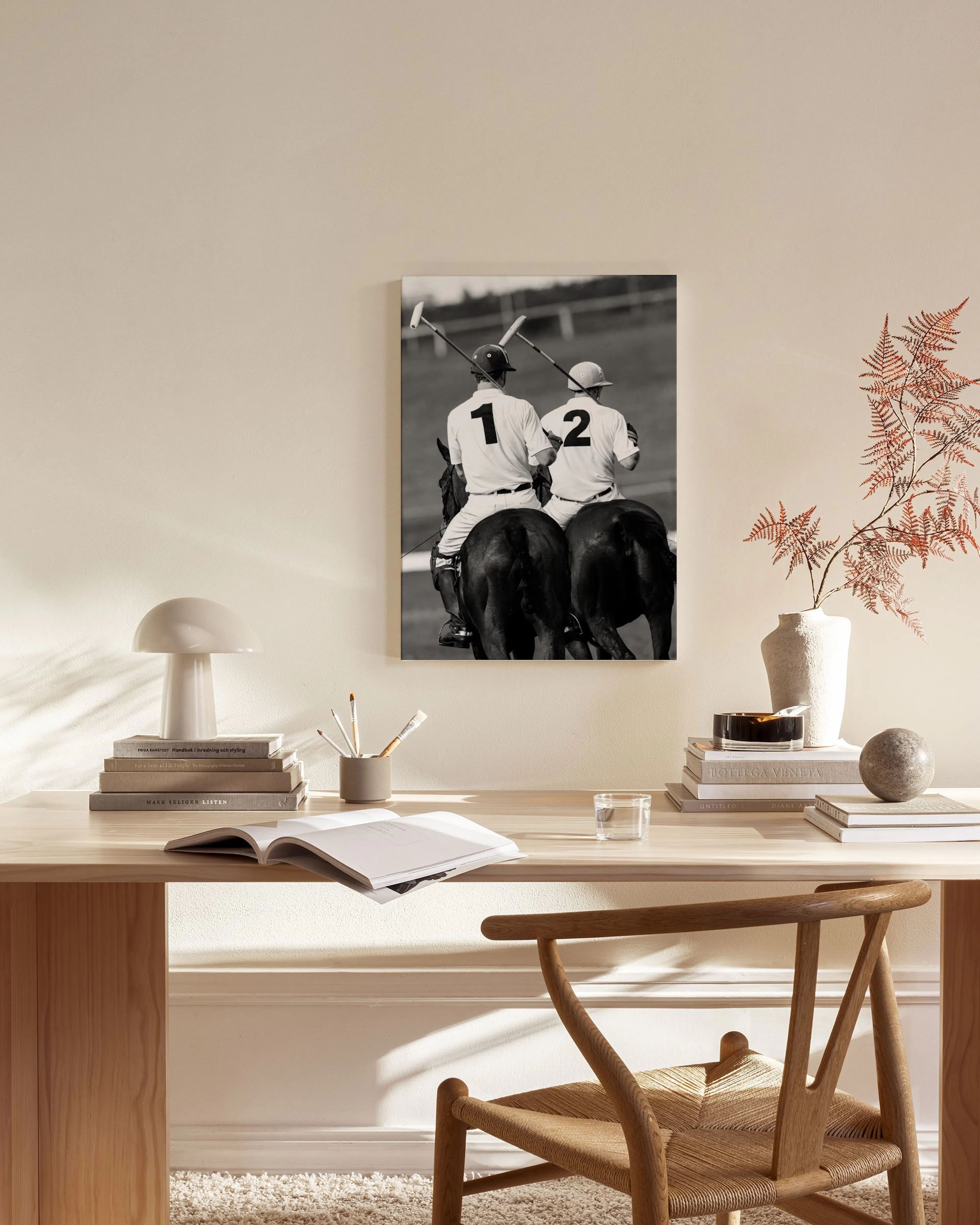 Schwarz-weiß Leinwandbild von zwei Polospielern auf Pferden, über einem Sideboard in einem Wohnzimmer.