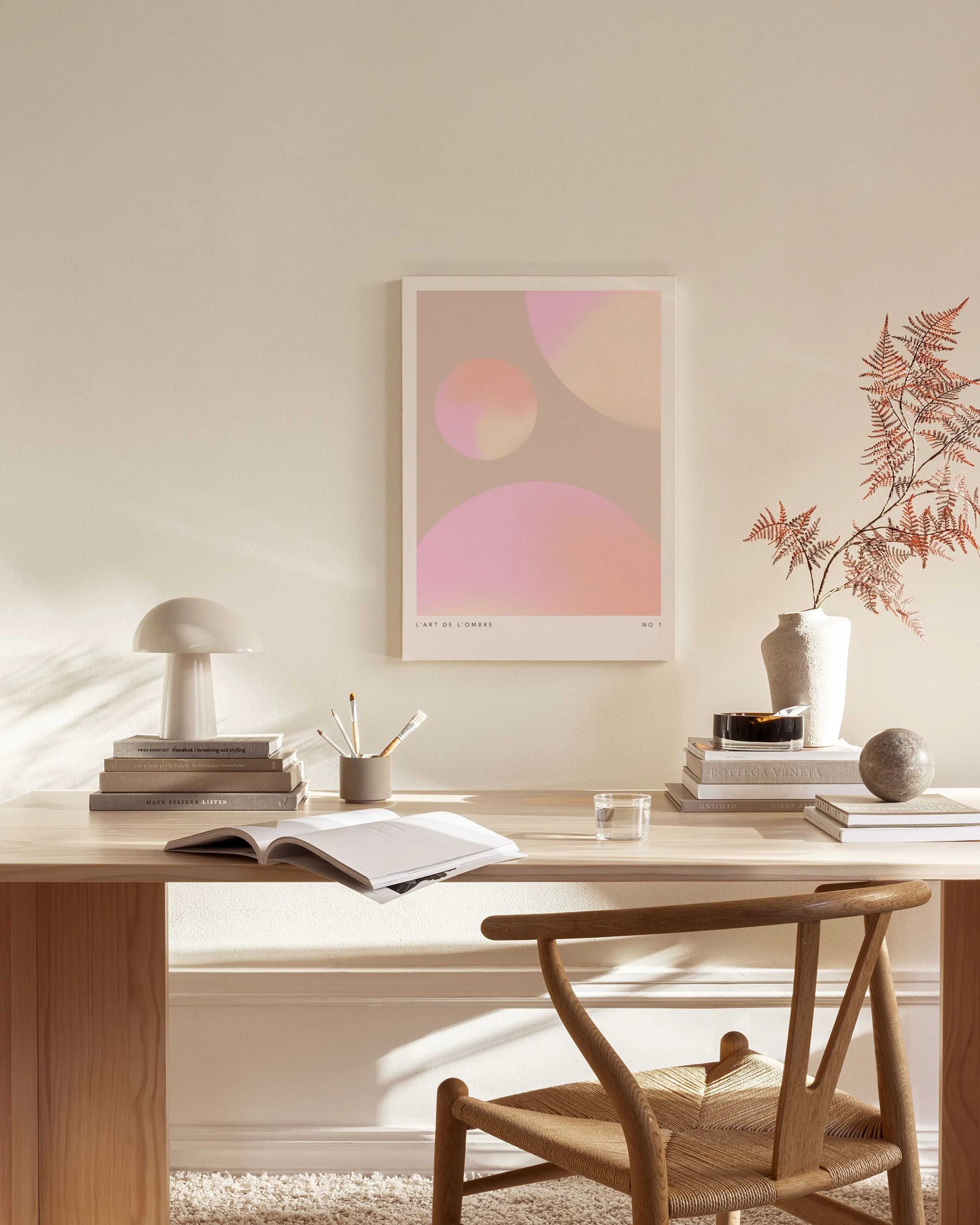 Stampa su tela con cerchi sfumati rosa e arancioni, appesa sopra una panca in legno in un soggiorno moderno.