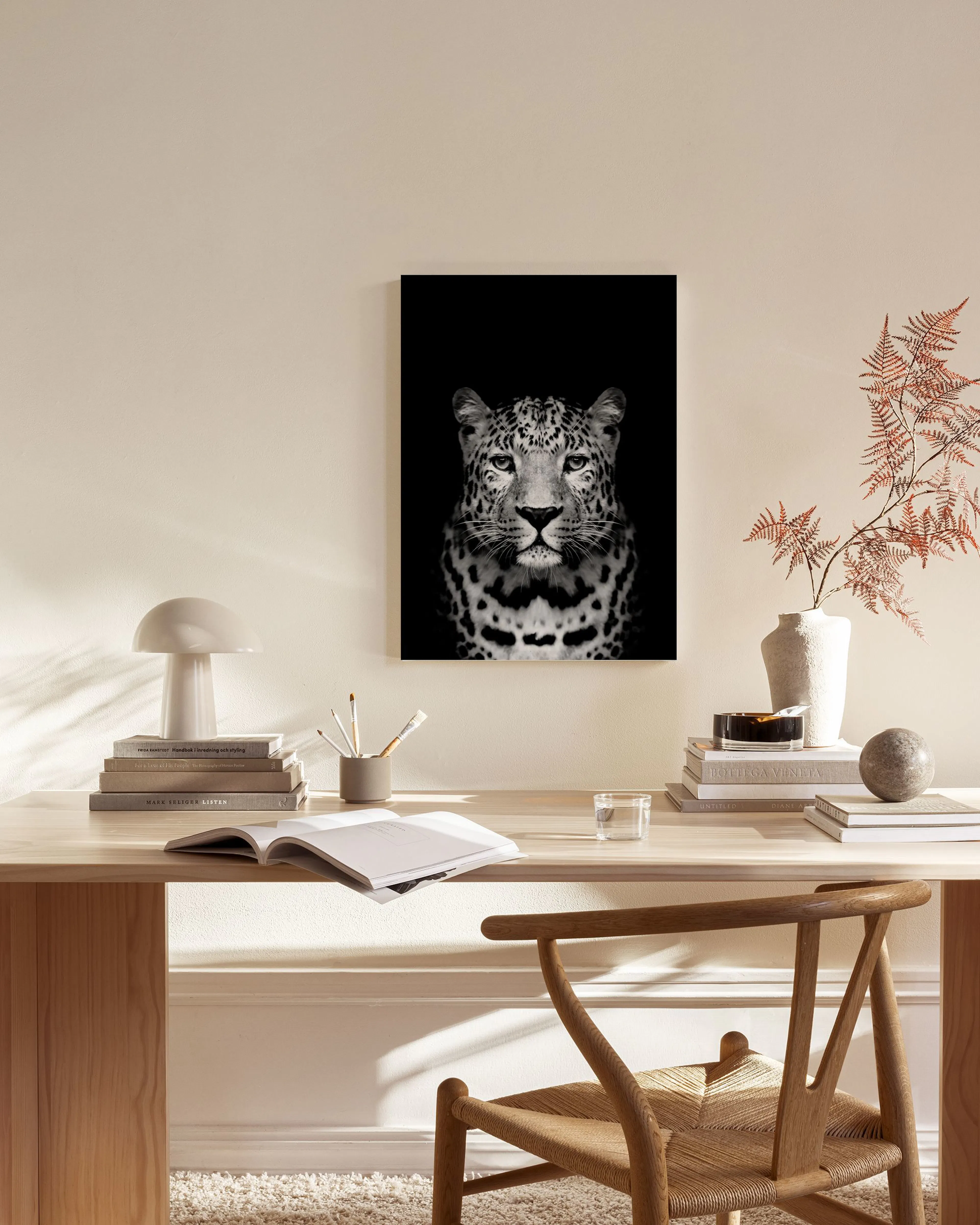 A black and white canvas print of a leopards face, hanging in a bright, modern living room.