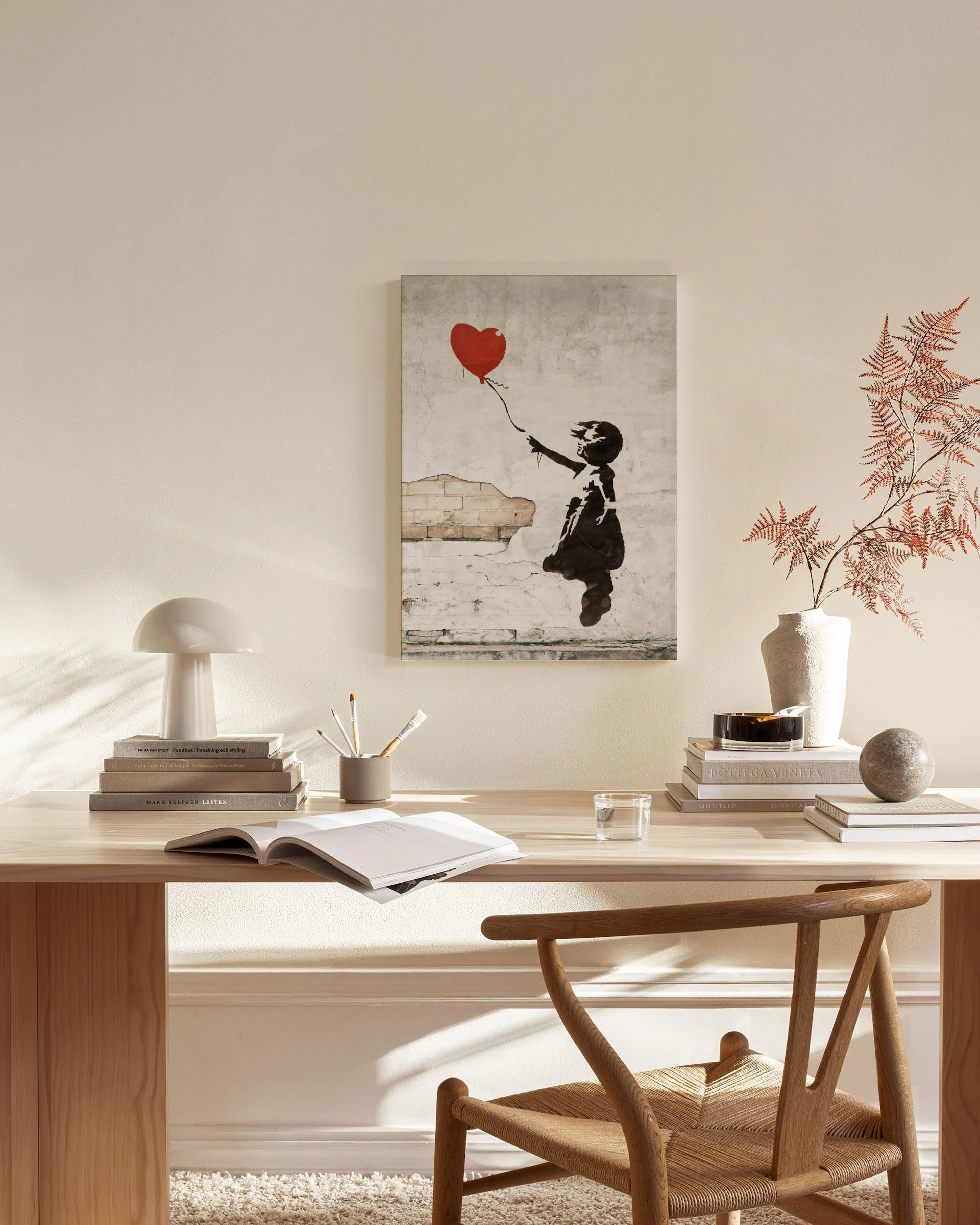 Toile La Jeune Fille au Ballon de Banksy, suspendue dans un salon moderne aux tons neutres, avec fauteuil en bois et table basse