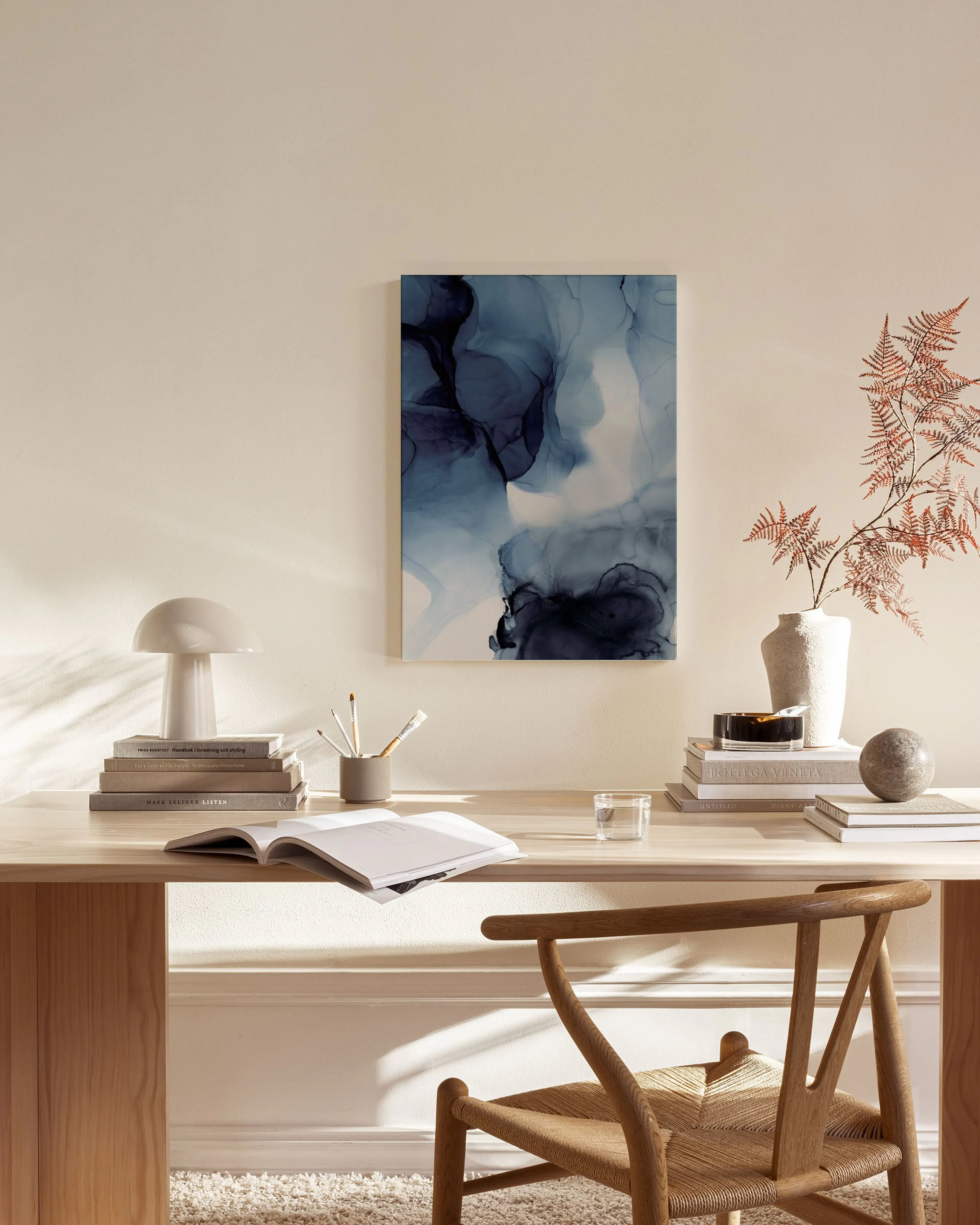 Leinwandbild mit dunkelblauen und hellblauen Farbwolken über einem Sideboard in einem modernen Wohnzimmer.