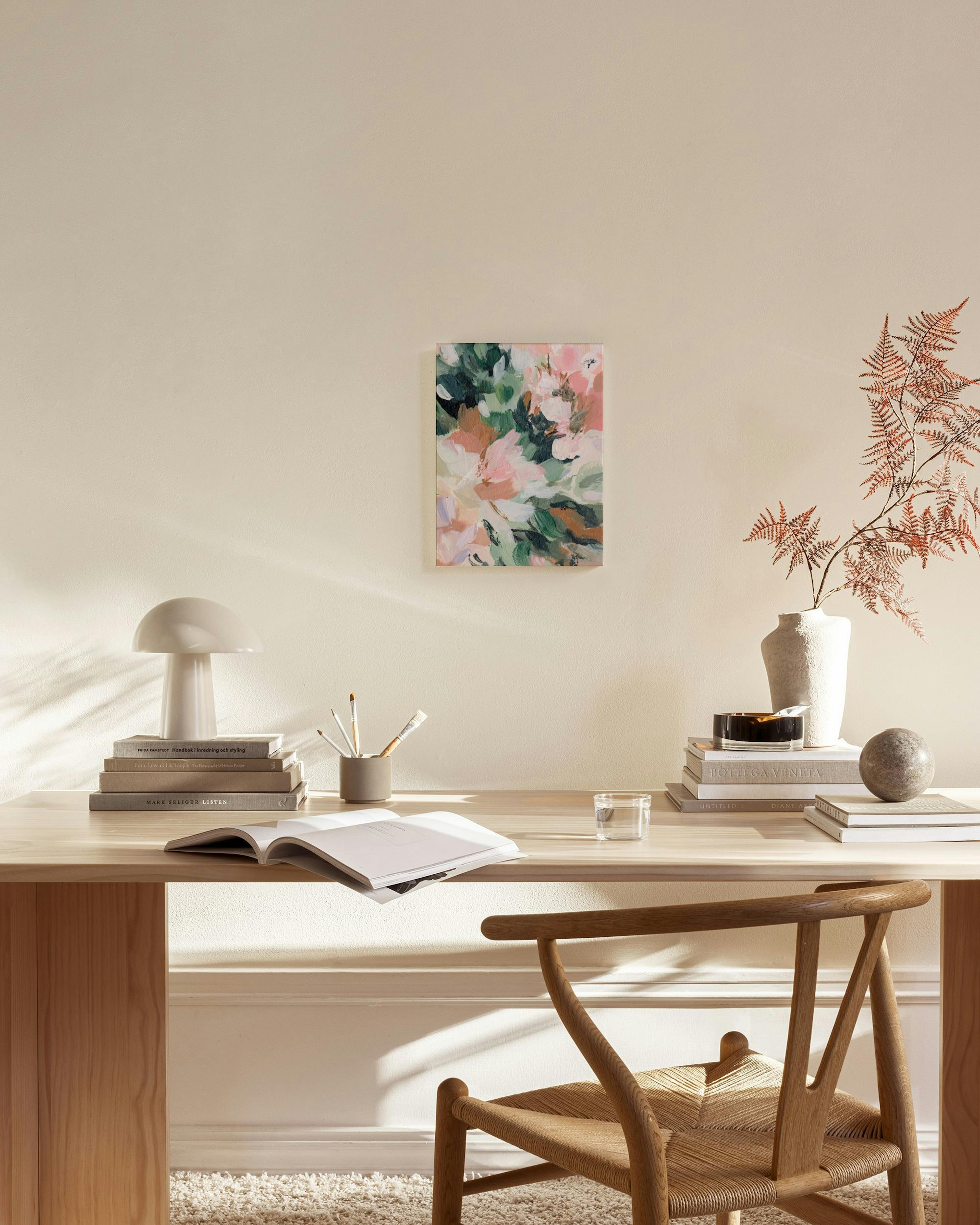 Abstract floral canvas print in pink, green, and white hues, hanging in a minimalist living room.