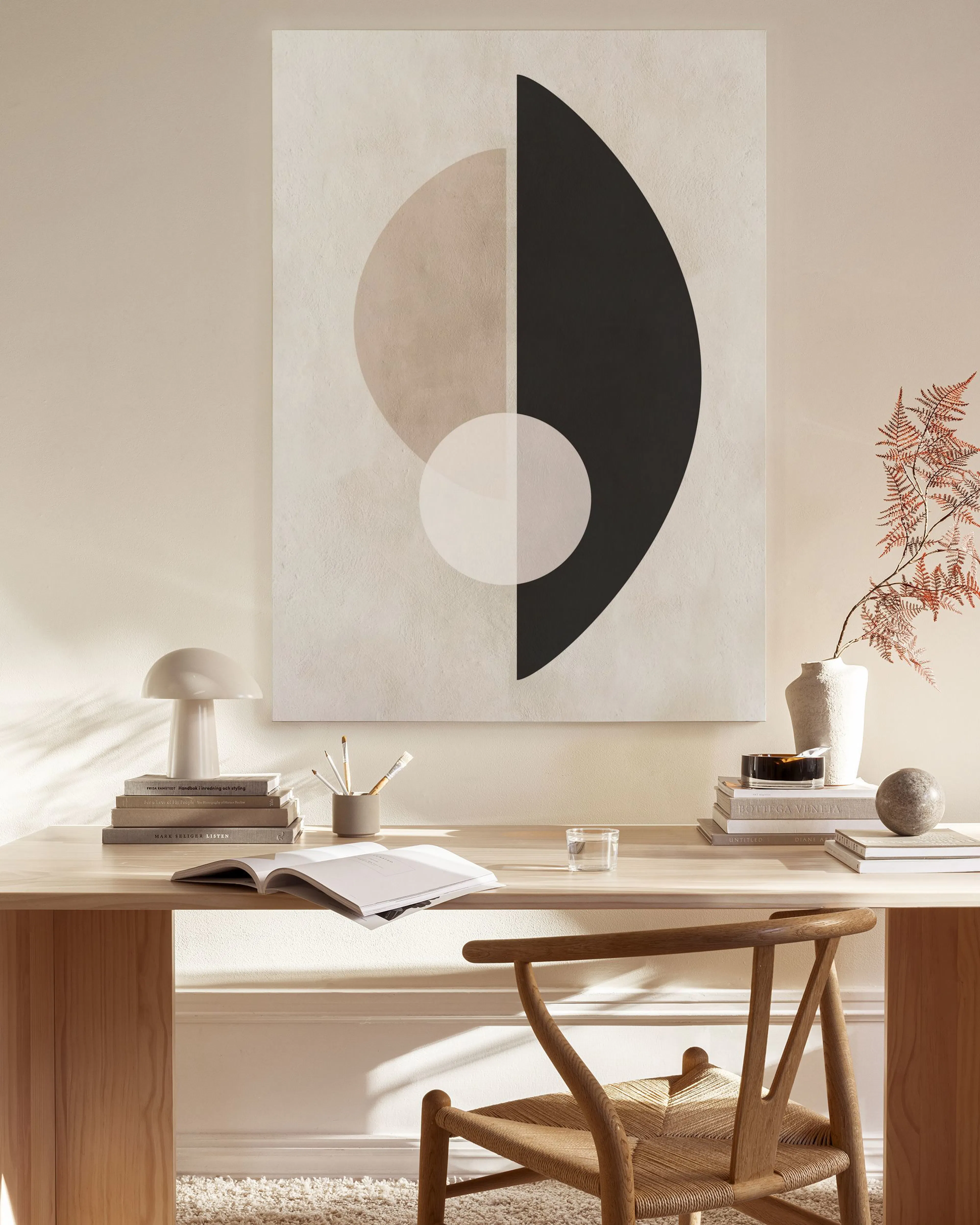 Stampa su tela con forme astratte nere, beige e bianche, appesa in un soggiorno moderno.