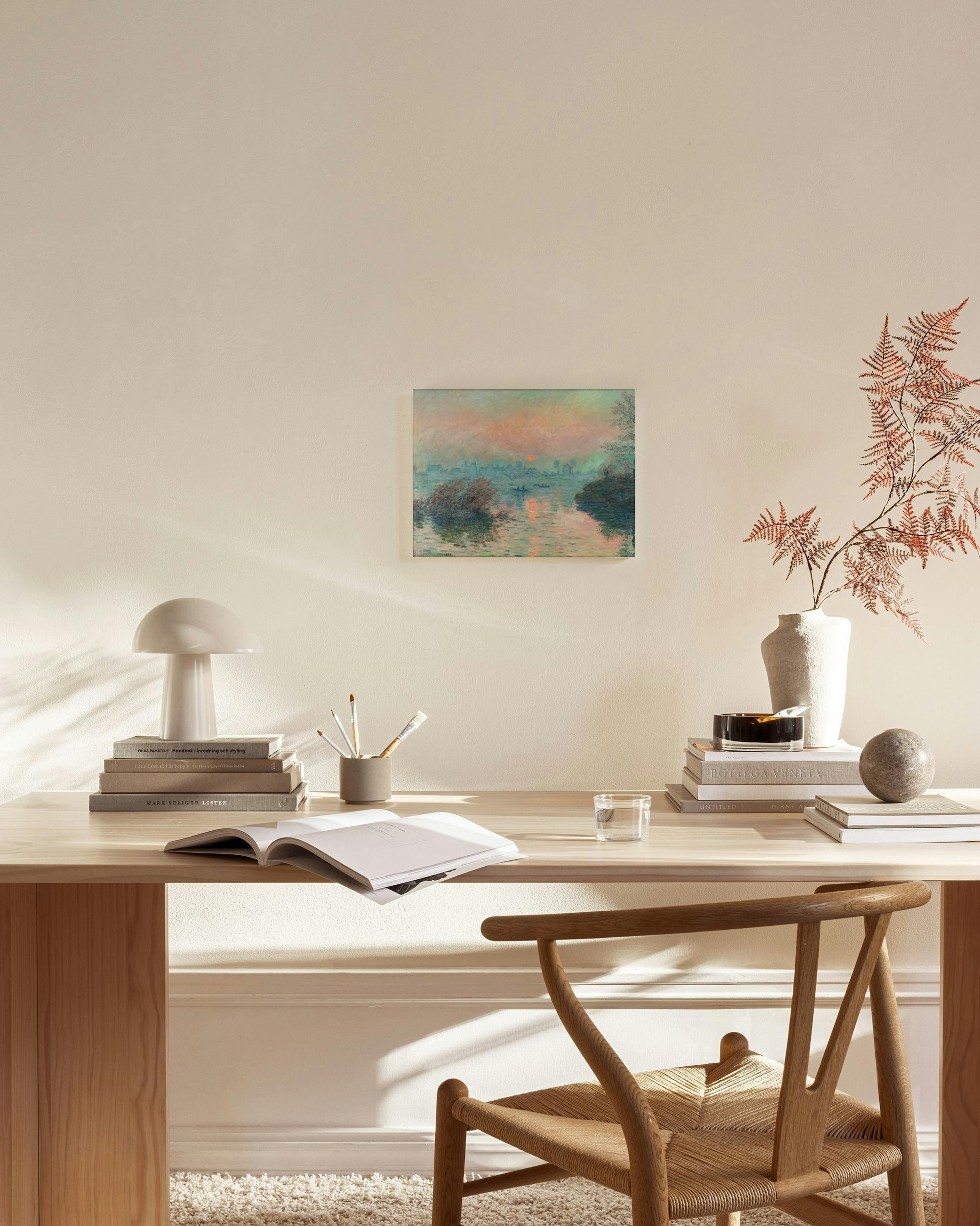 Obraz na plátne zobrazujúci západ slnka nad riekou s člnmi, zavesený v modernej obývacej izbe nad drevenou komodou.