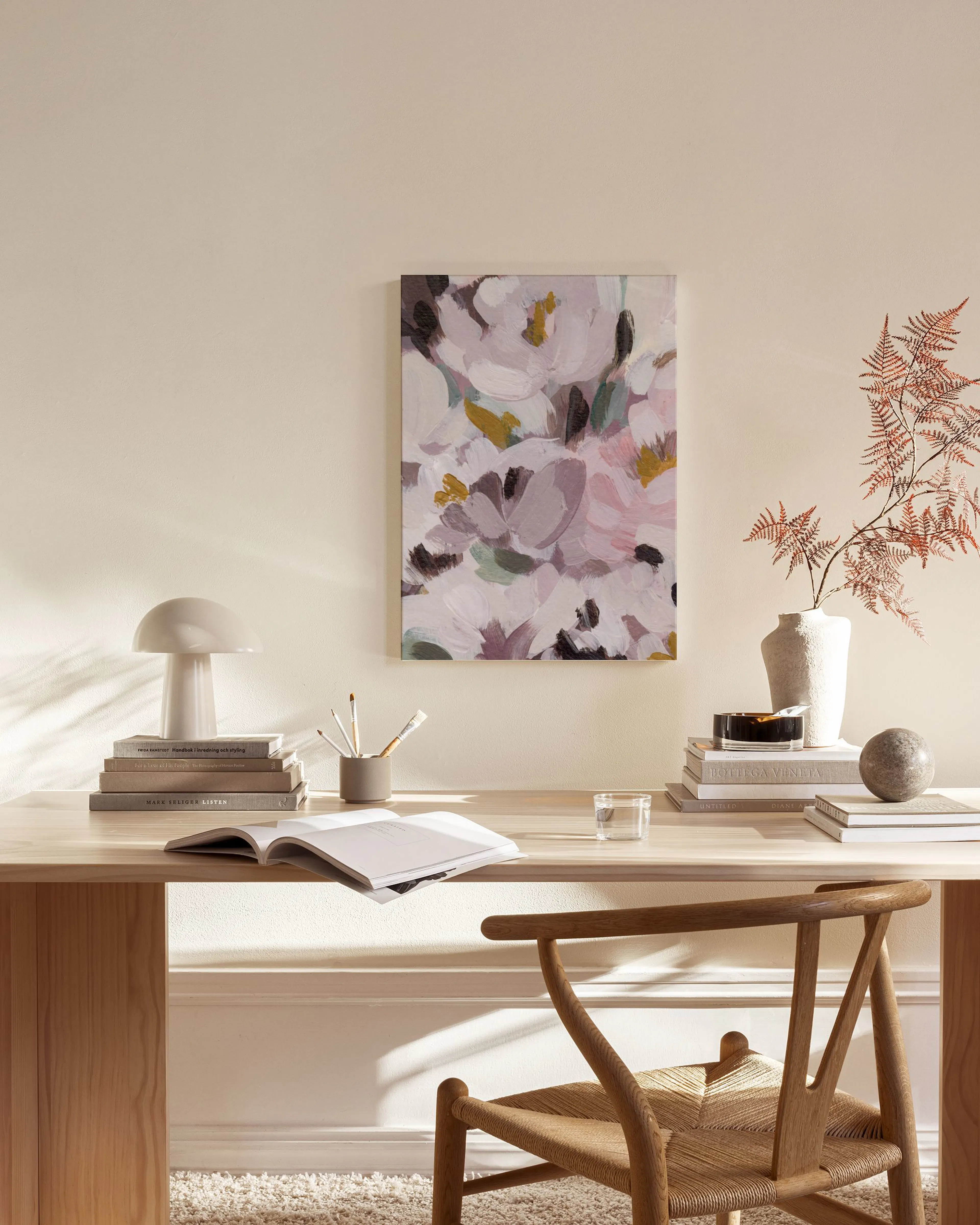Lerretbilde med abstrakte blomster i lilla og rosa nyanser, henger over et sidebord i en moderne stue.