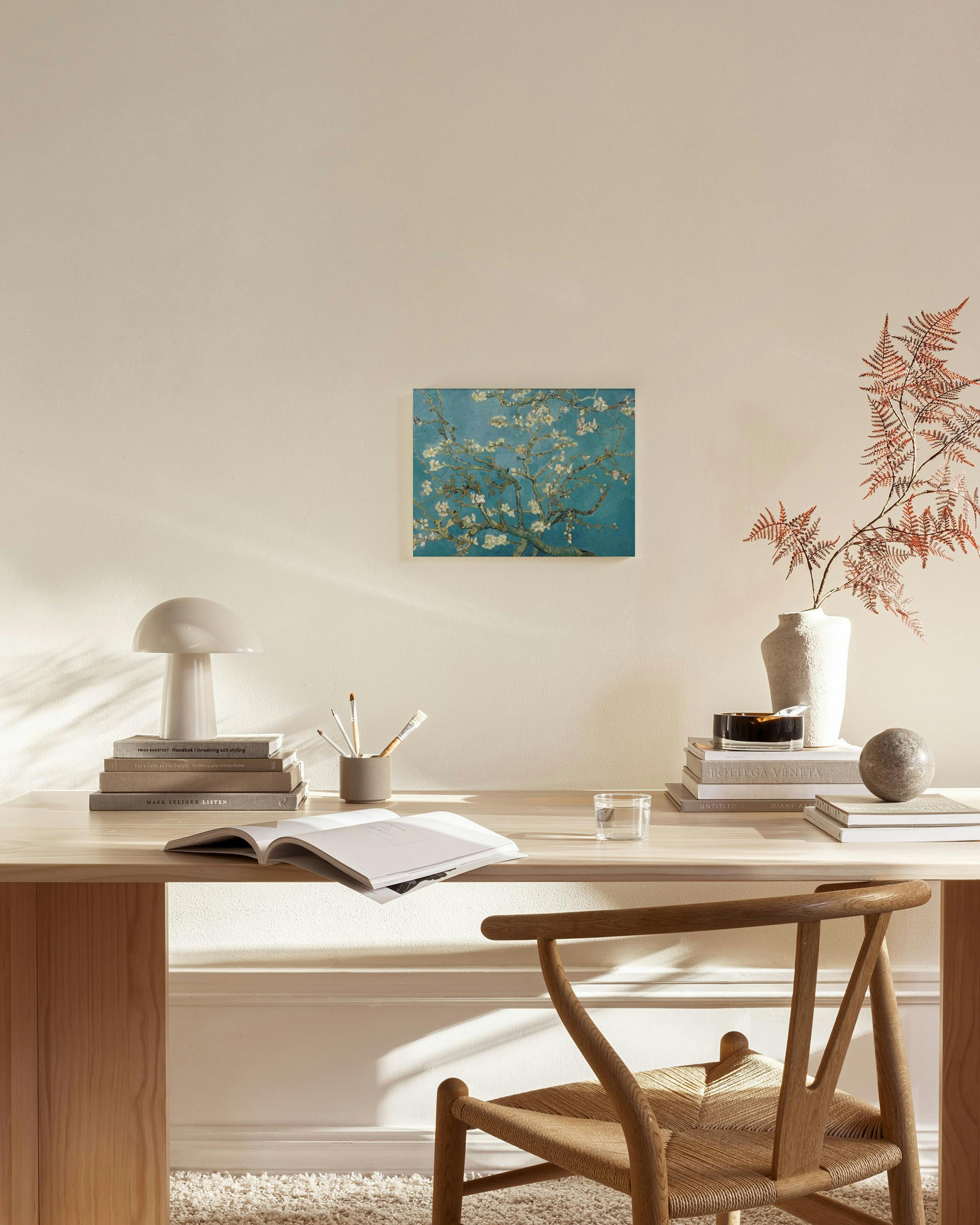 A canvas print of Van Goghs Almond Blossom, with white blossoms against a blue sky, hanging in a bright, modern living room.