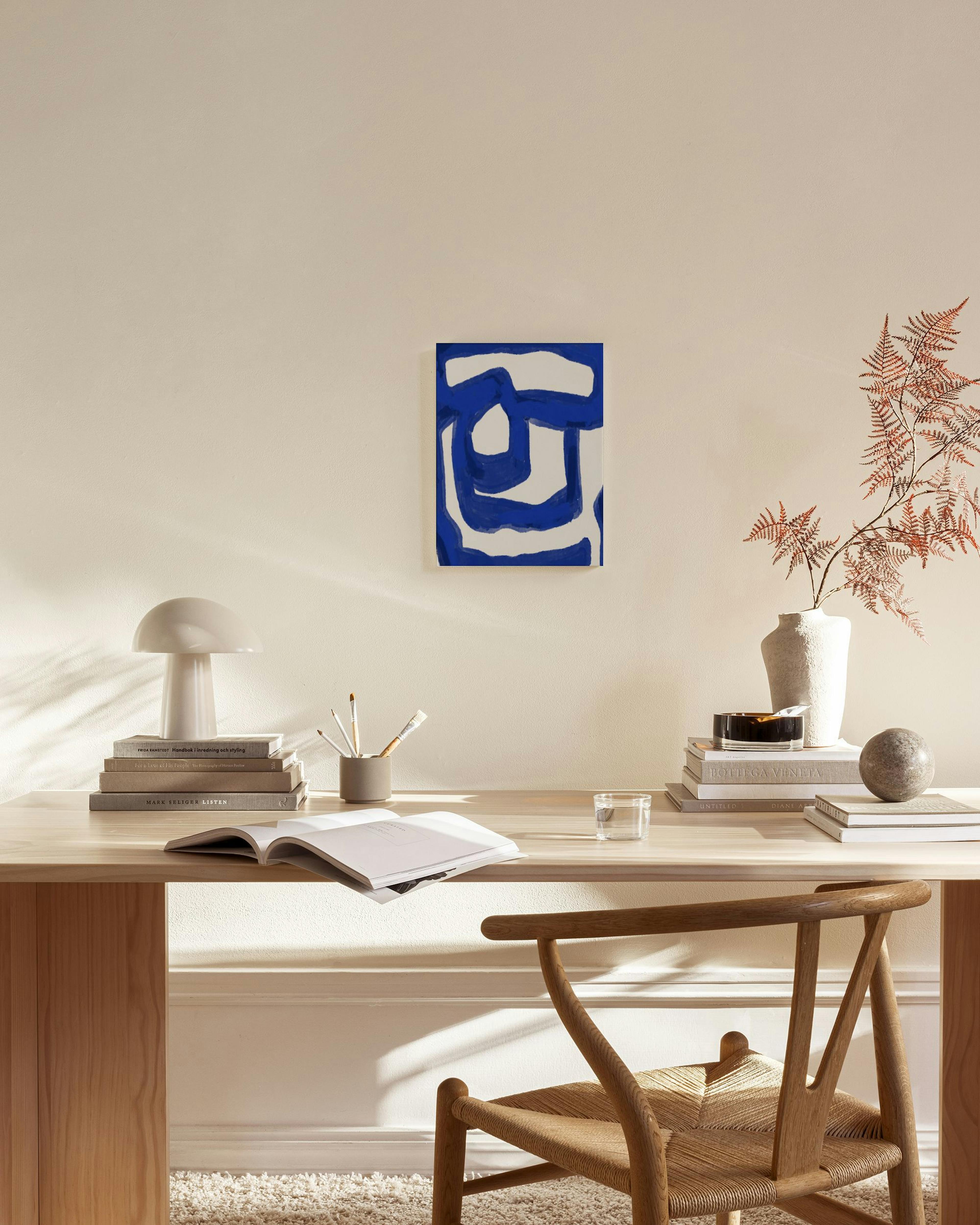 Stampa su tela astratta blu e bianca, appesa sopra una credenza in un soggiorno moderno.