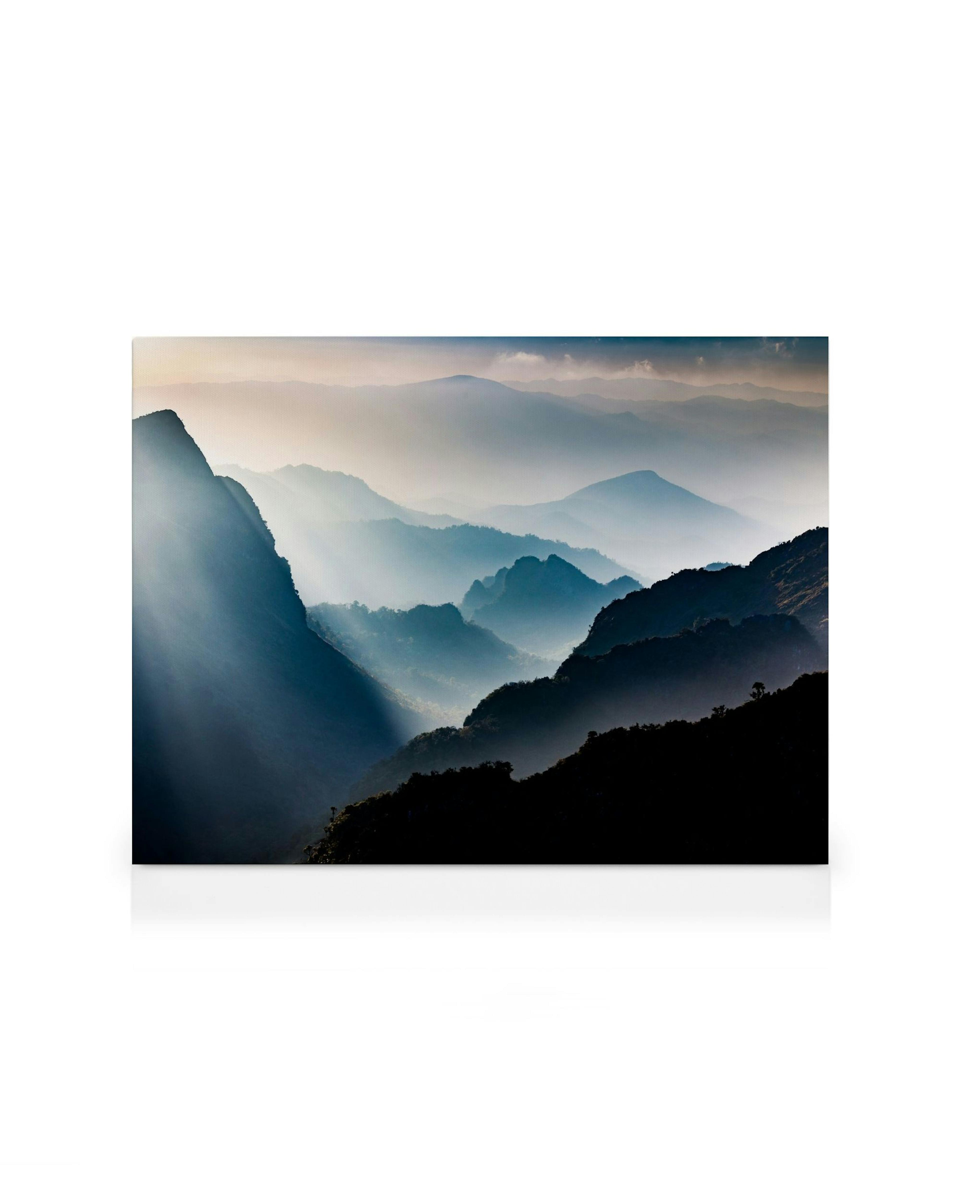 Foggy mountain view canvas print with sun rays piercing through the misty peaks, creating a dramatic landscape art piece.