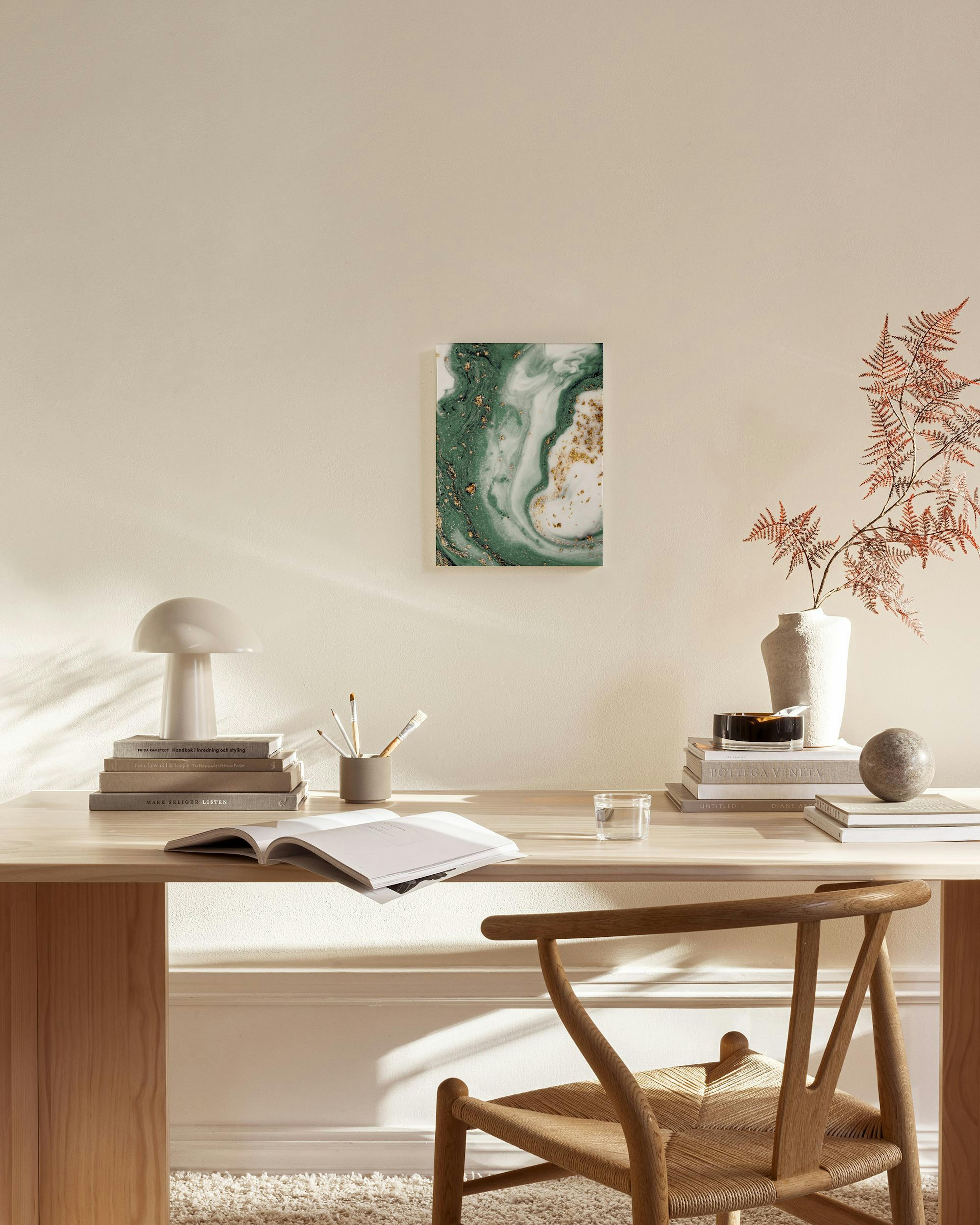 Lienzo abstracto de arte fluido en tonos verde esmeralda, blanco y salpicaduras doradas, colgado en una sala moderna.