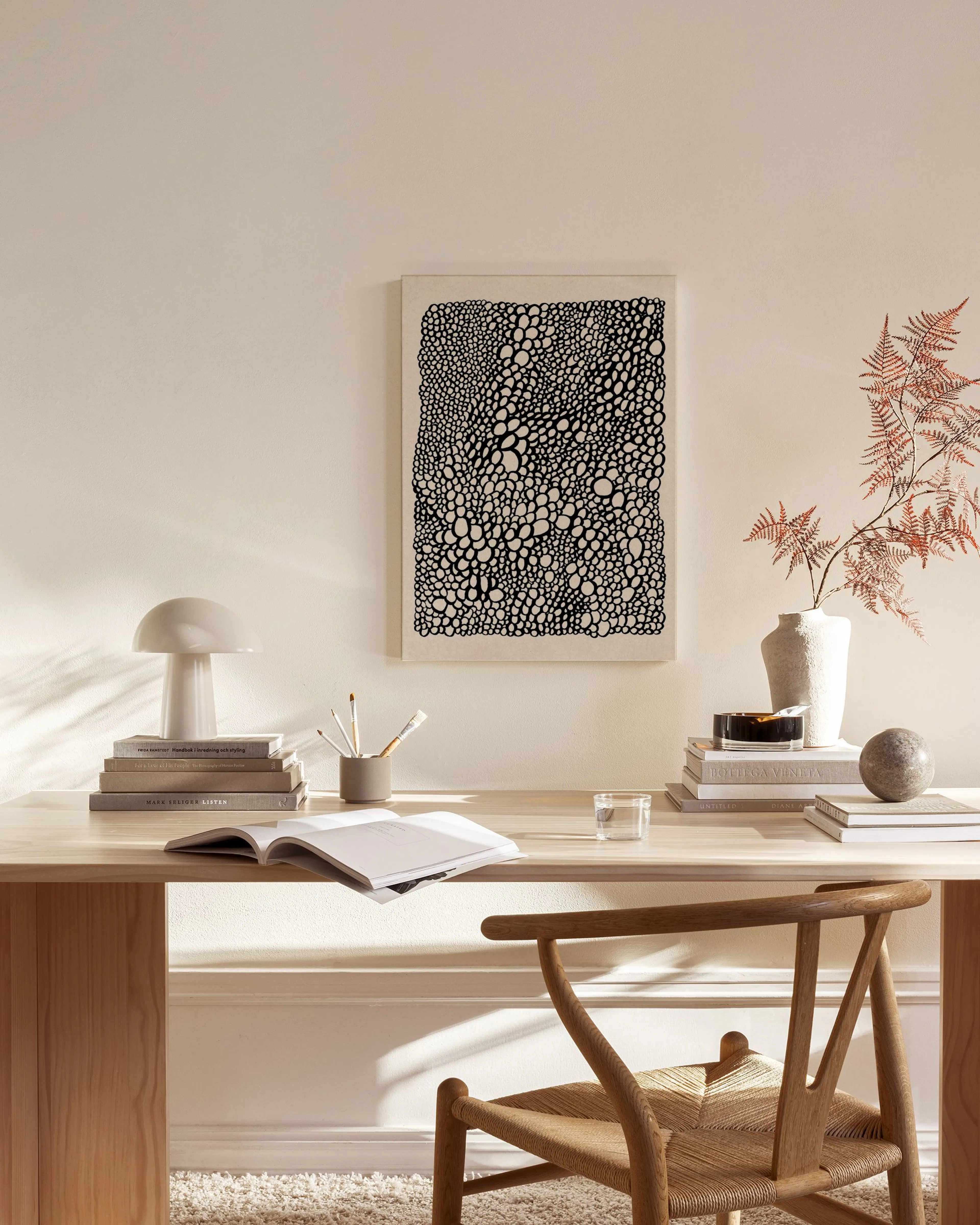 Tela decorativa com padrão orgânico de bolhas pretas e brancas, na parede de uma sala de estar minimalista com móveis de madeira