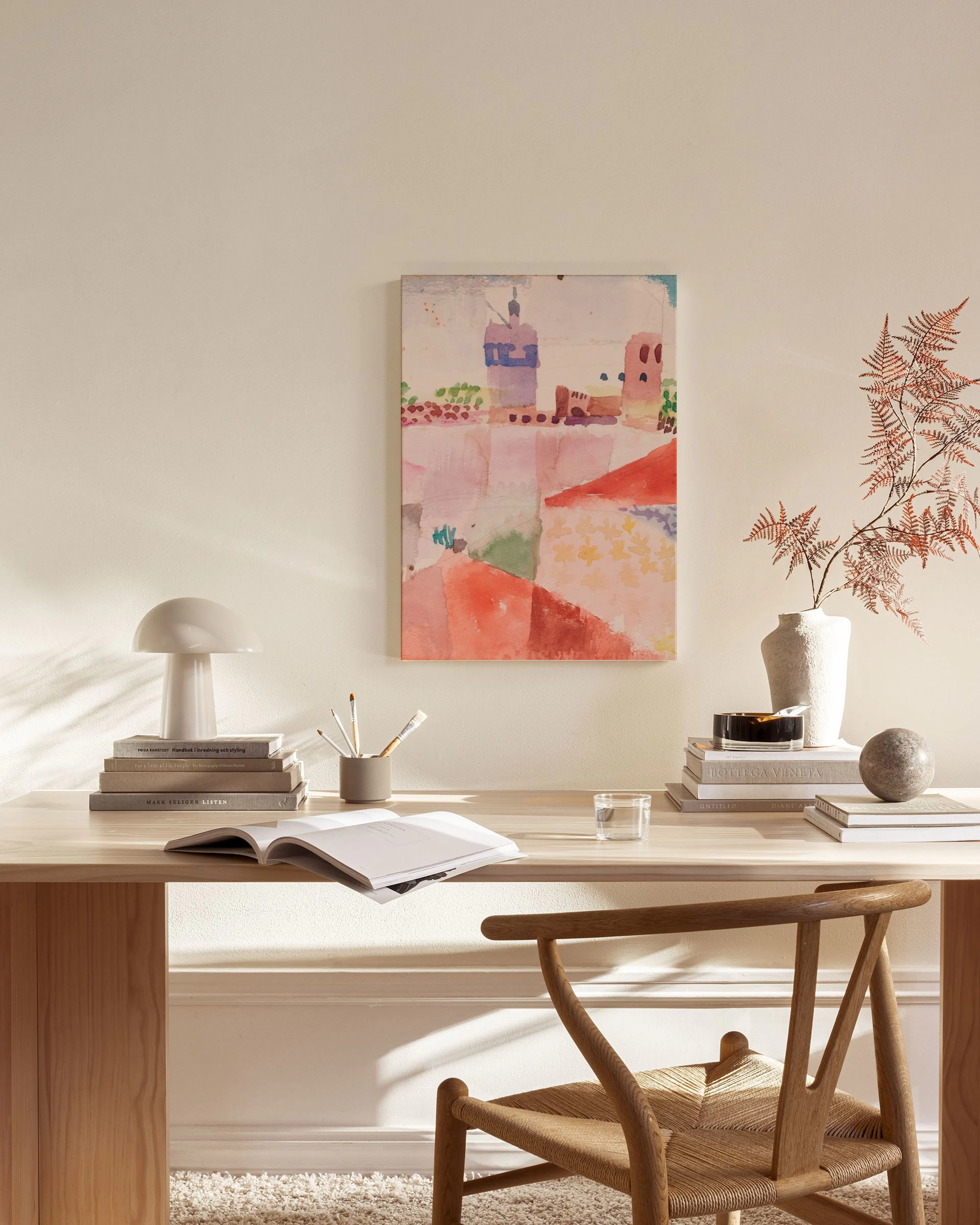 Lienzo abstracto de paisaje urbano con tonos rosados, rojos y verdes, colgado sobre un mueble de madera en una sala de estar.