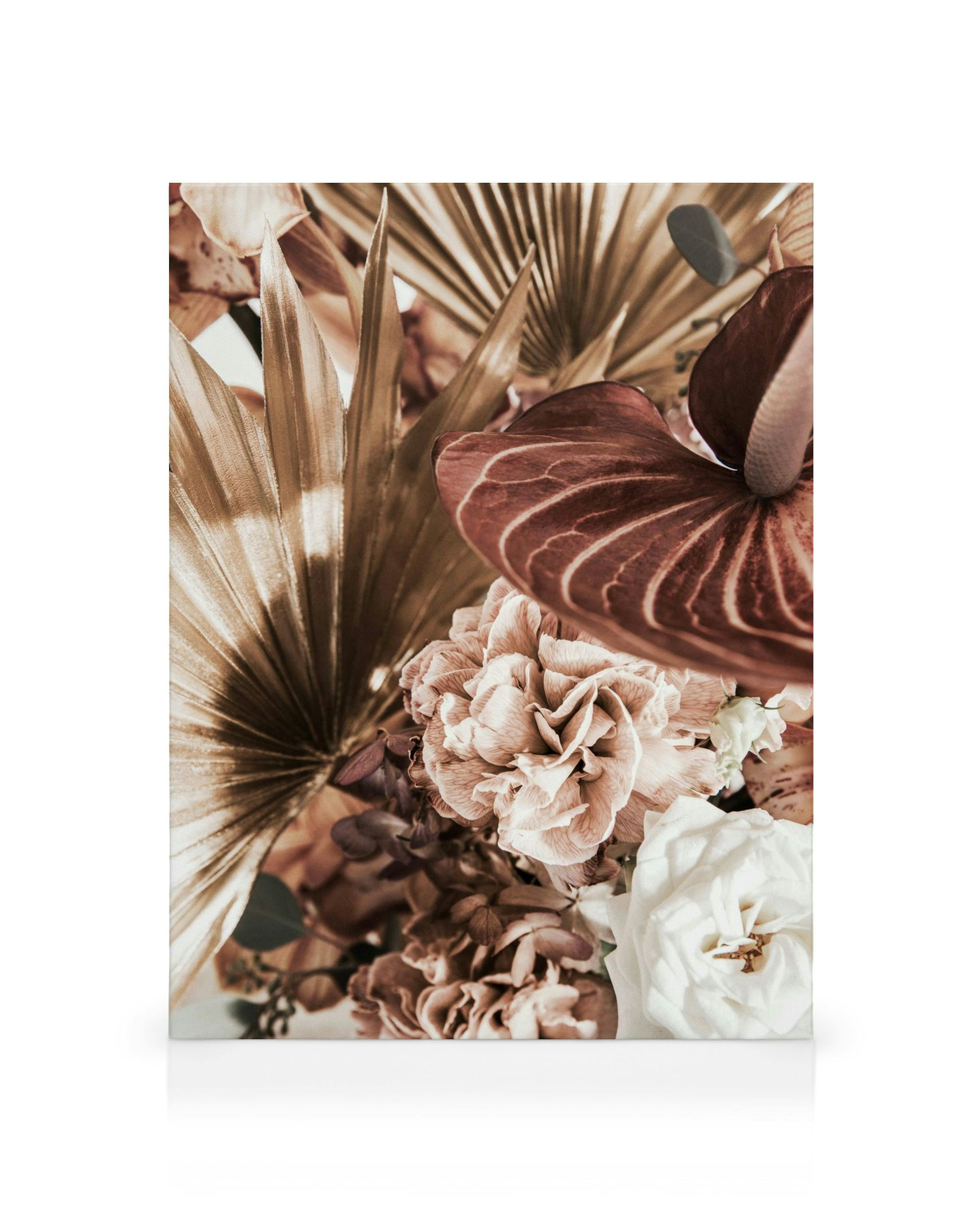 Ramo de flores en tonos apagados de marrón, rosa, blanco y dorado, con hojas de palma y anturio.