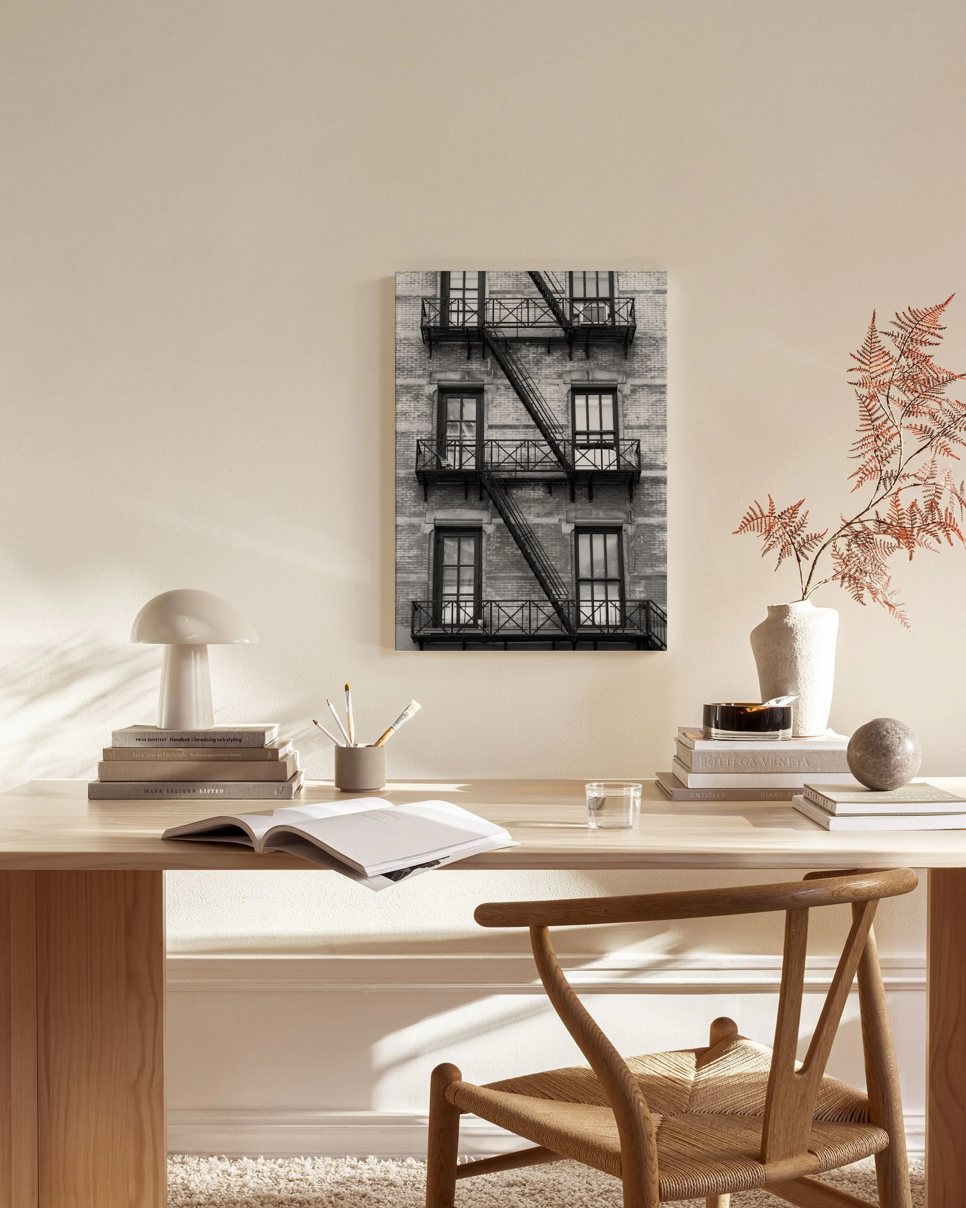 A black and white canvas print of a building exterior with fire escapes, hanging in a minimalist living room.