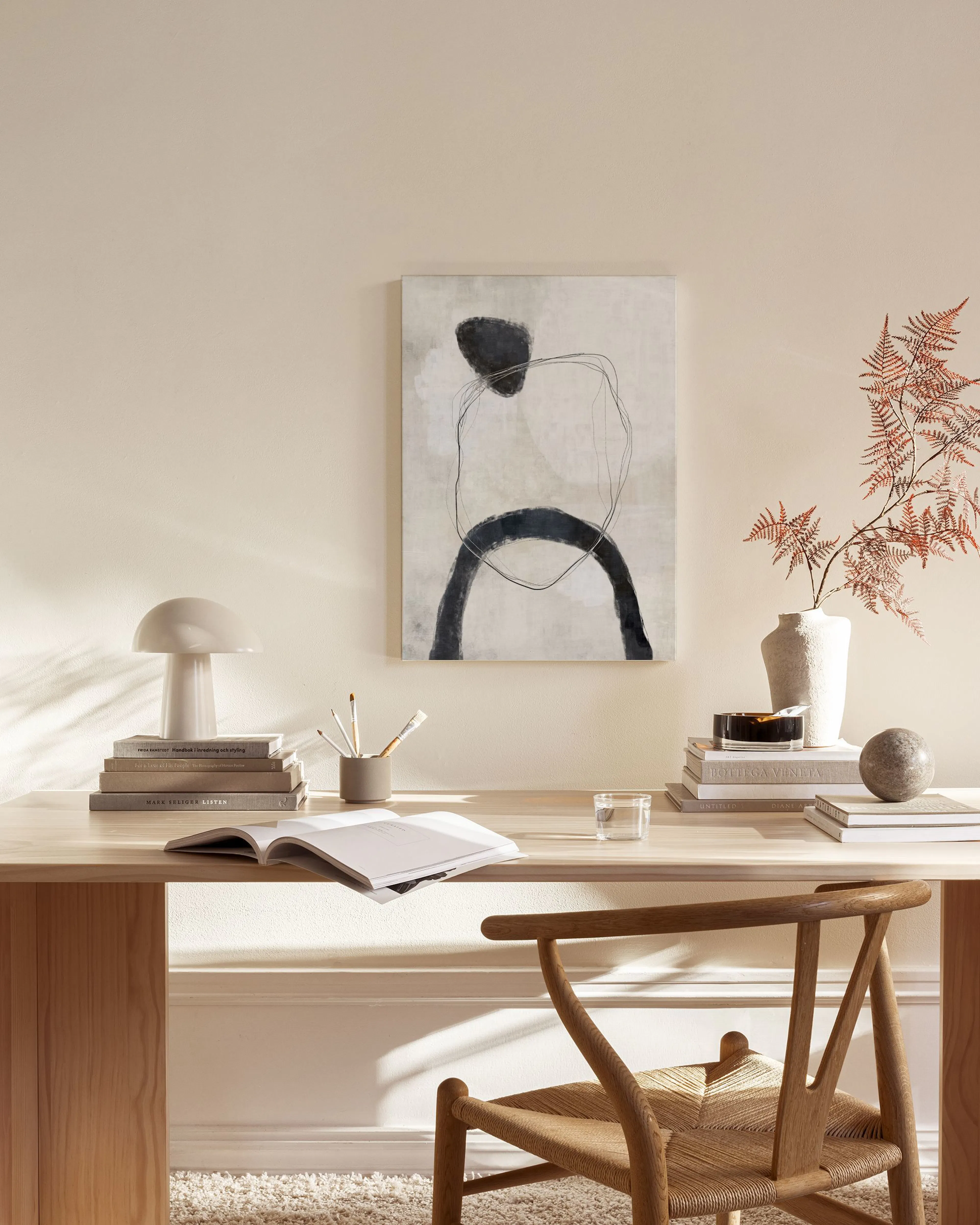 Neutral abstract canvas print with black and charcoal shapes and lines, hanging in a minimalist living room.