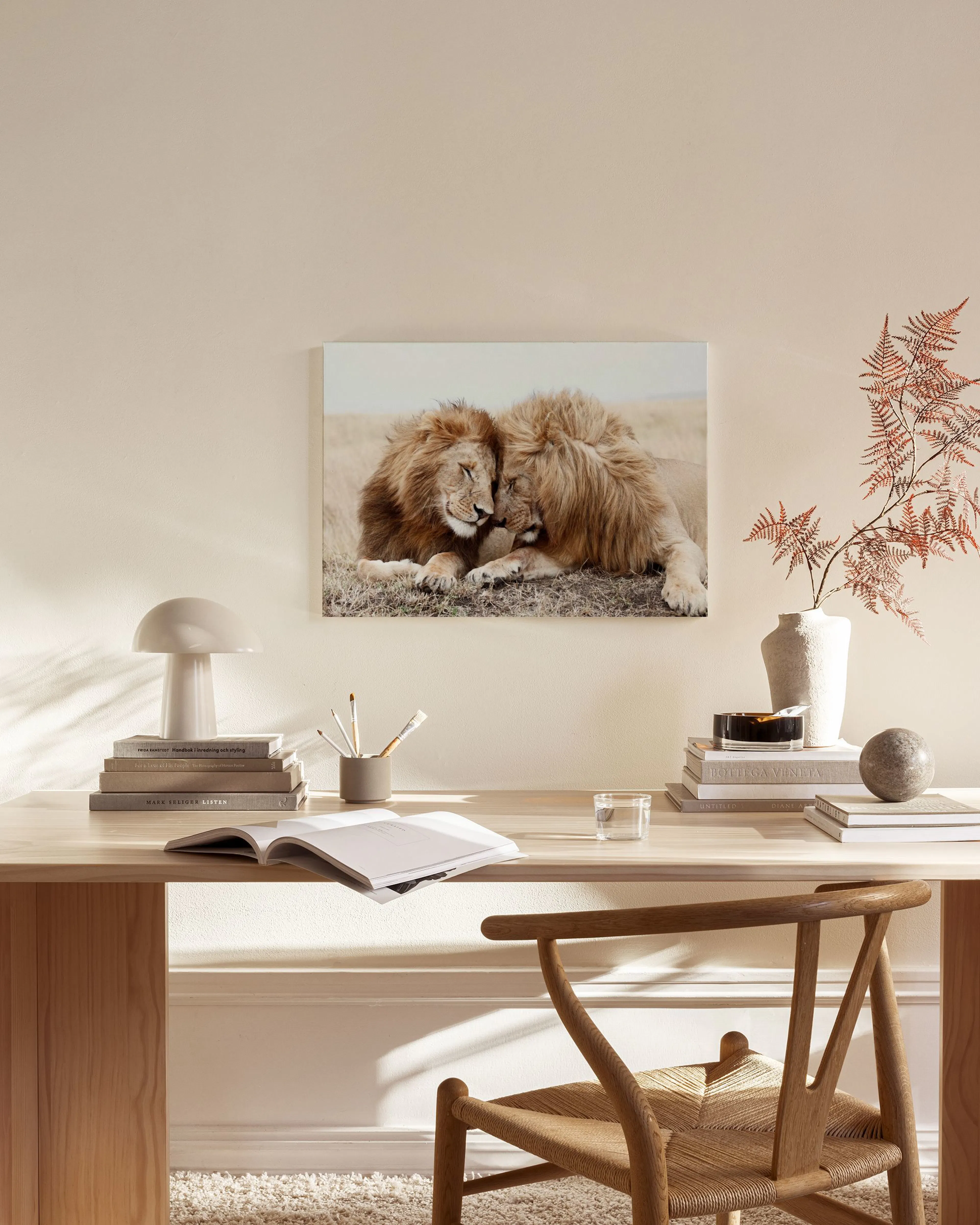 Leinwandbild mit zwei Löwen in Zuneigung, in einem hellen, modernen Wohnzimmer über einem Sideboard.