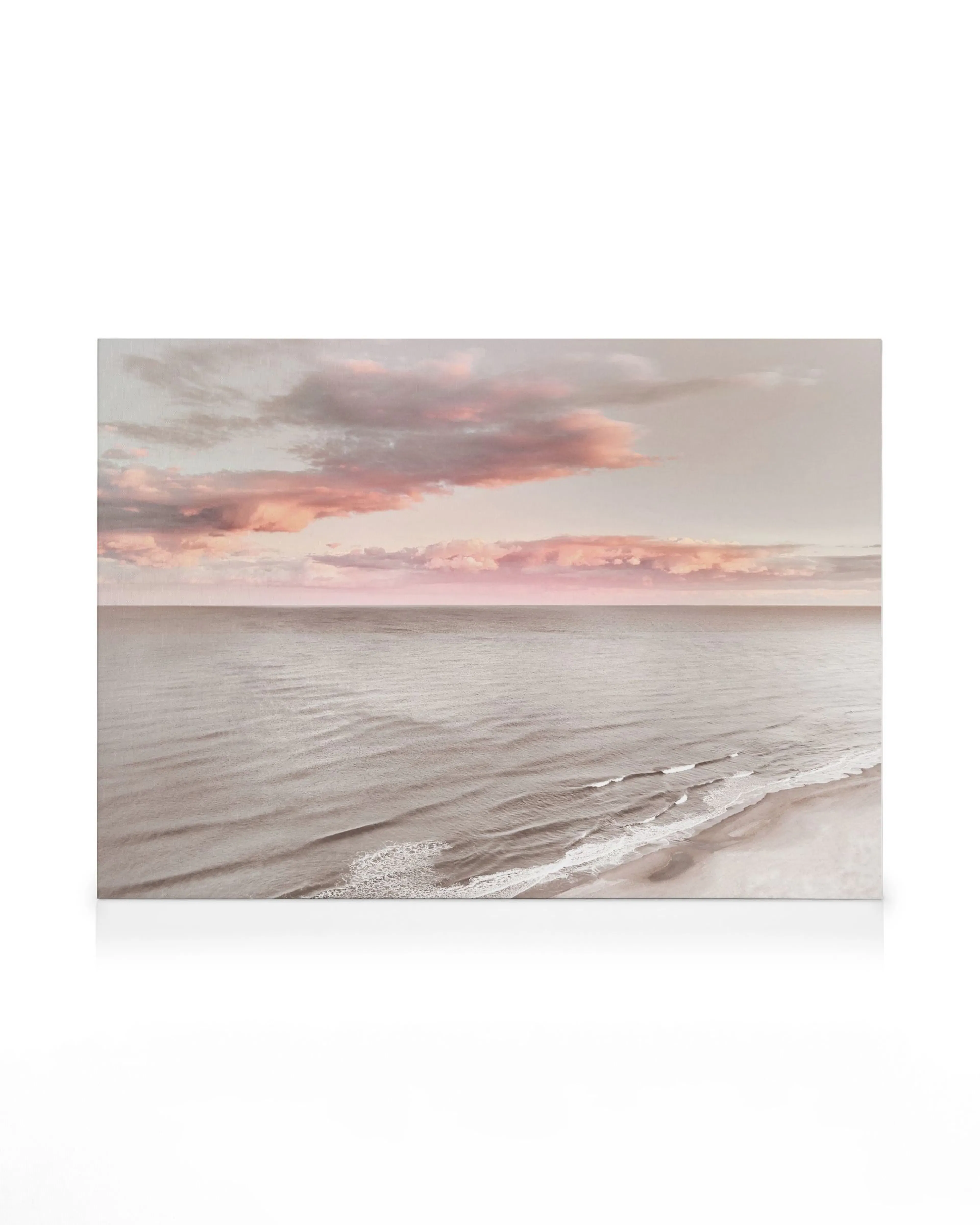 Drømmende havlærred med rolige bølger og pink-orange solnedgangshimmel over havet, strandudsigt.
