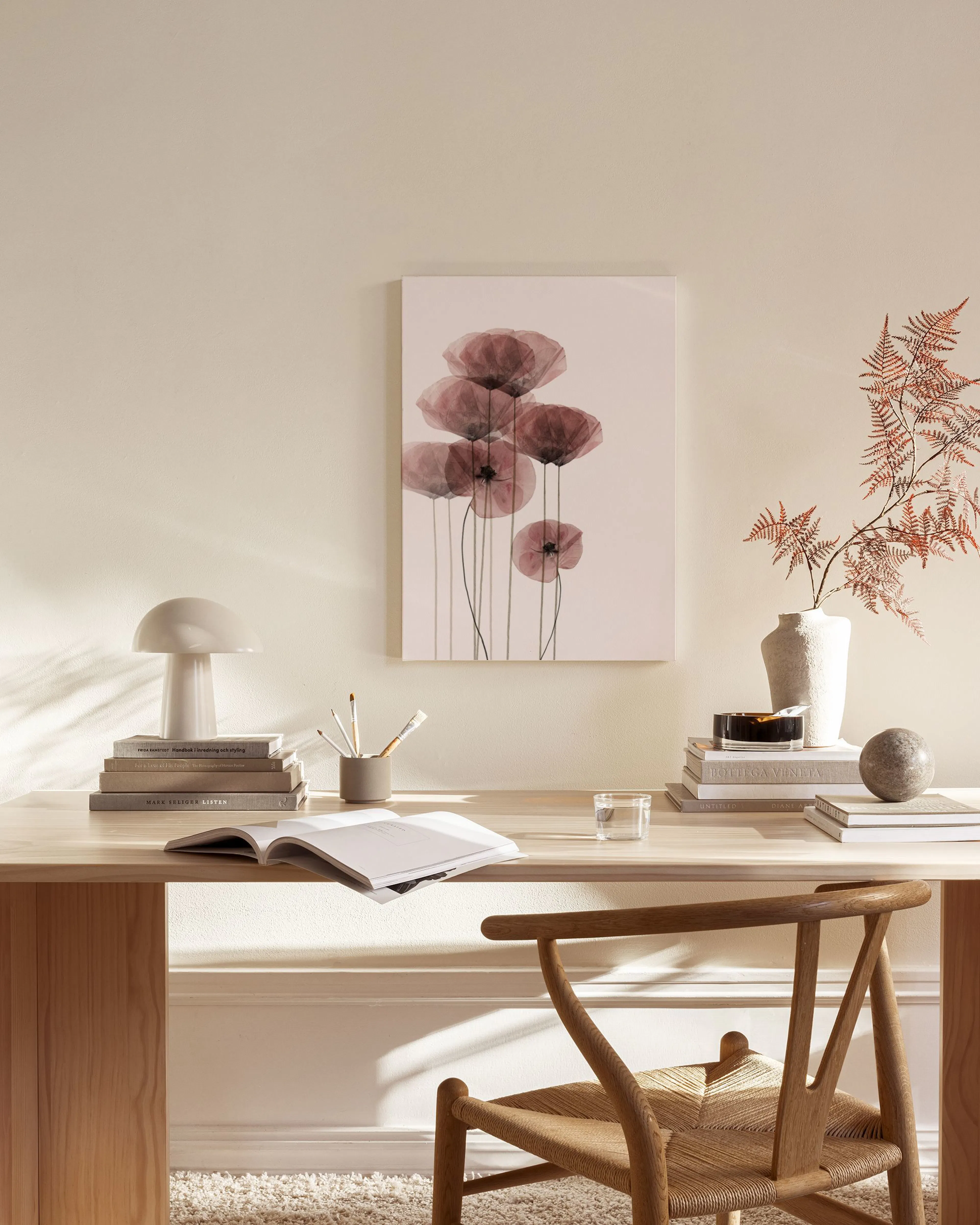 Stampa su tela con papaveri trasparenti rosa-violacei, appesa in un soggiorno moderno sopra una credenza in legno.