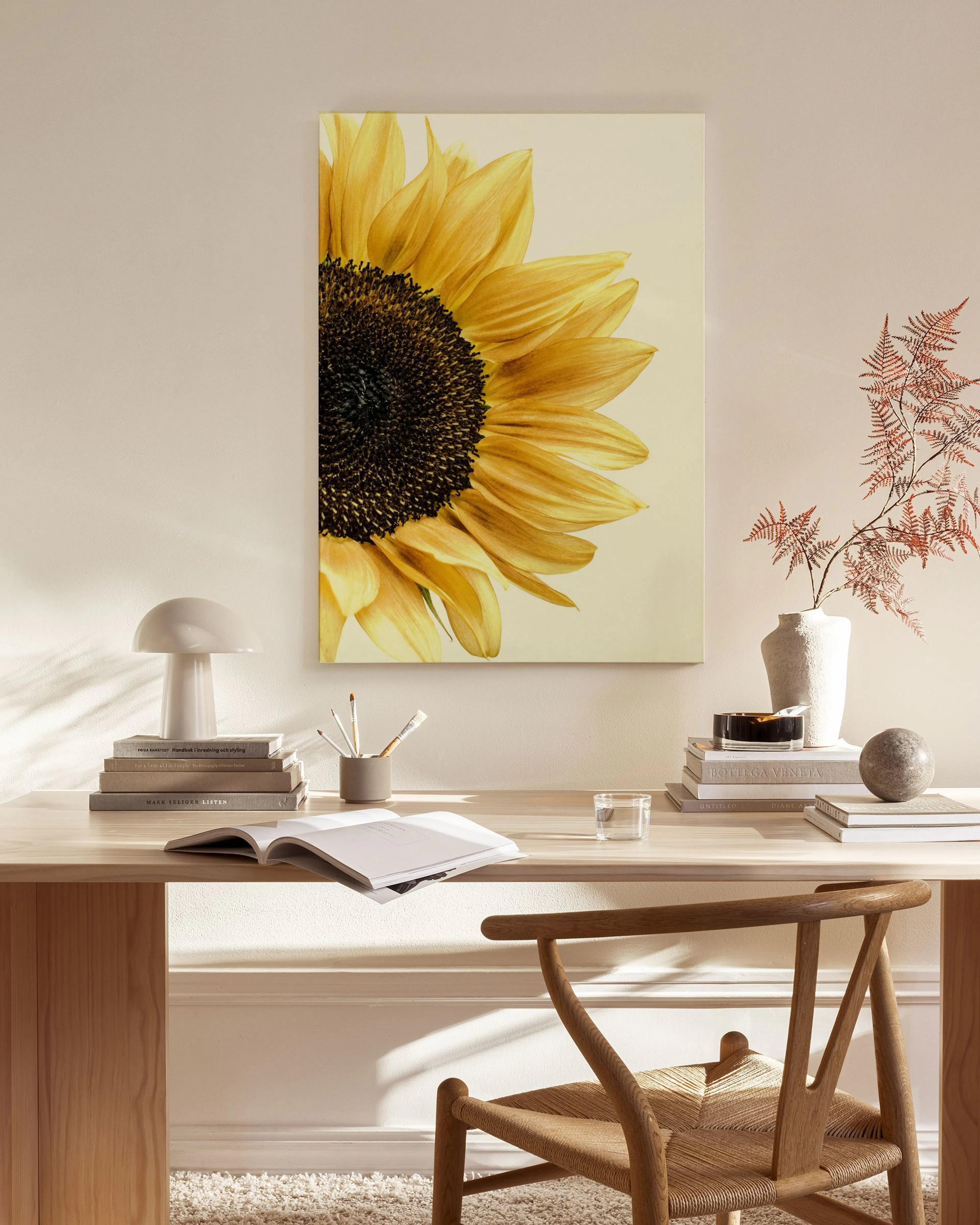 Canvas met een close-up van een zonnebloem, hangend in een lichte woonkamer boven een houten dressoir.