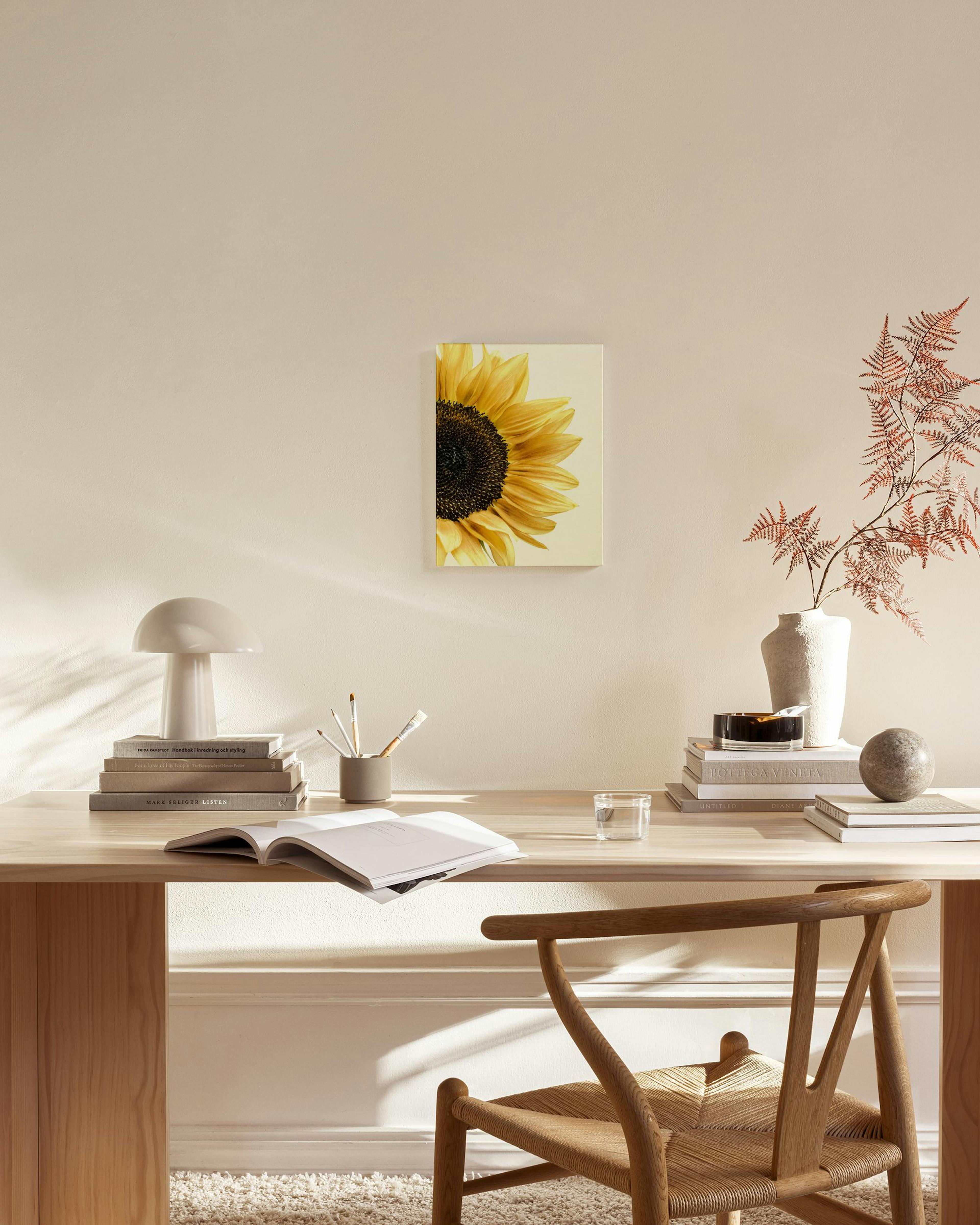 Obraz na plátne so žiarivou žltou slnečnicou, zavesený nad drevenou komodou v modernom obývacom priestore.
