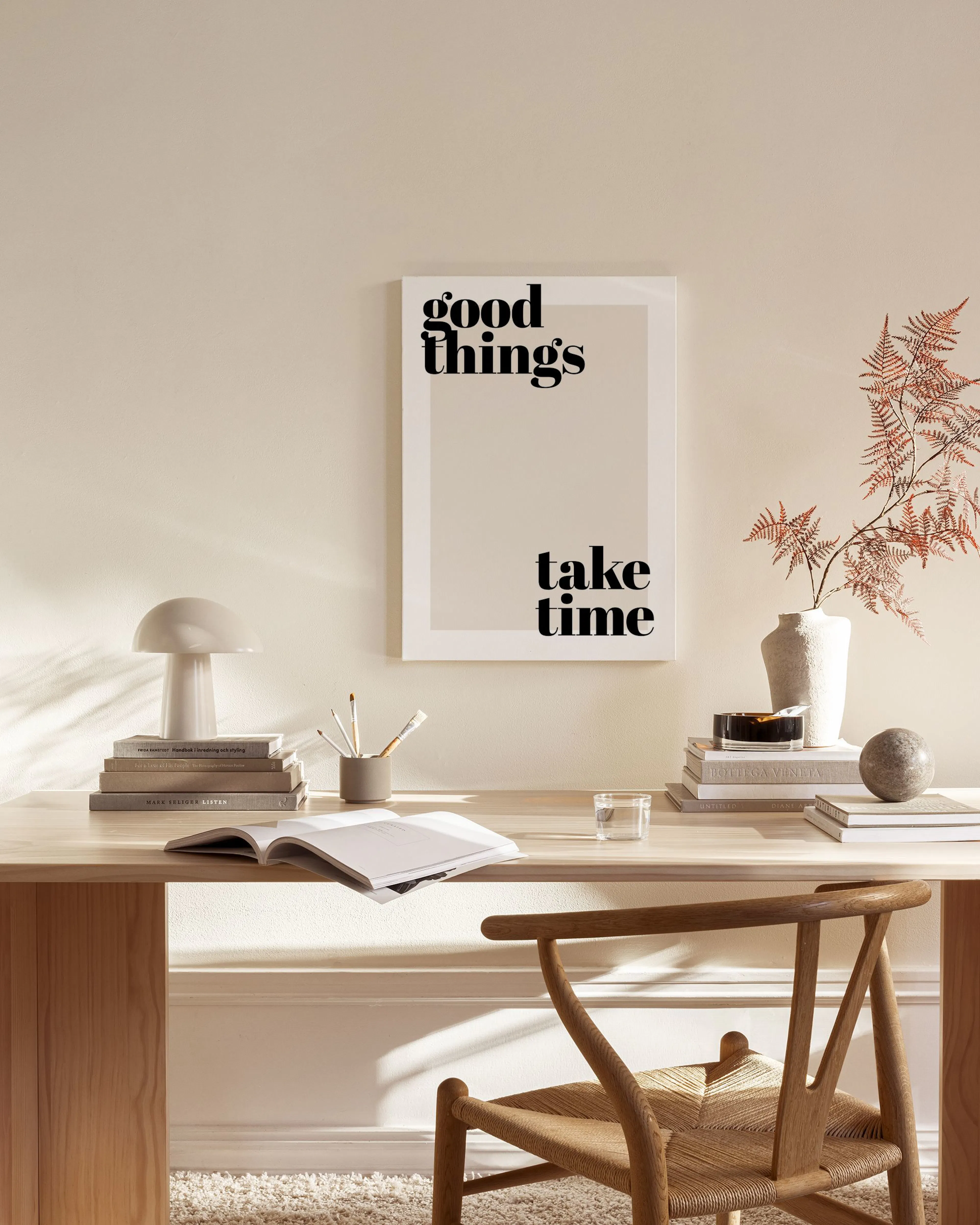 Toile murale avec linscription « good things take time » en noir sur fond beige, suspendue dans un salon moderne.