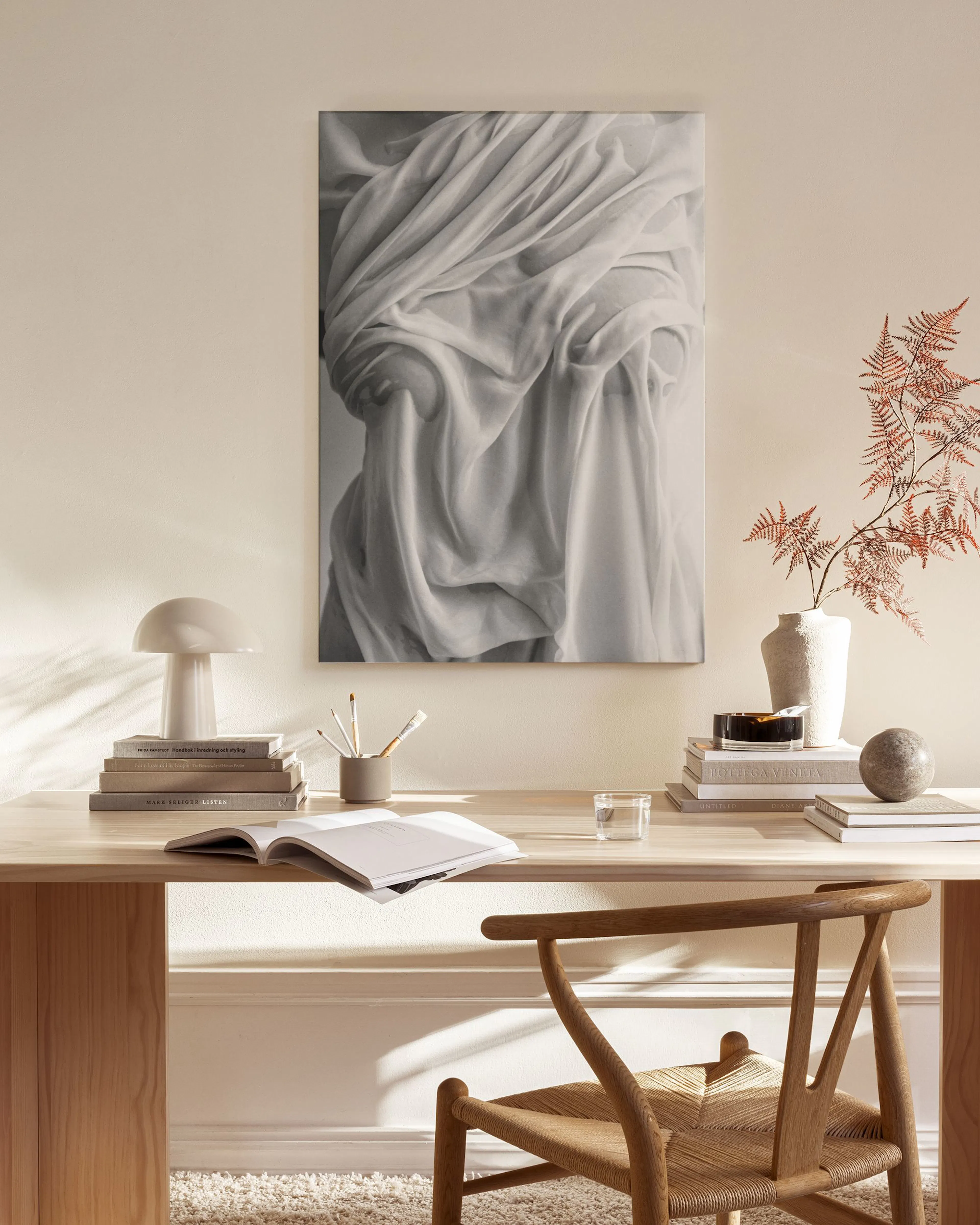 Zwart-wit canvas van gedrapeerde stof met plooien, hangend boven een houten dressoir in een moderne woonkamer.
