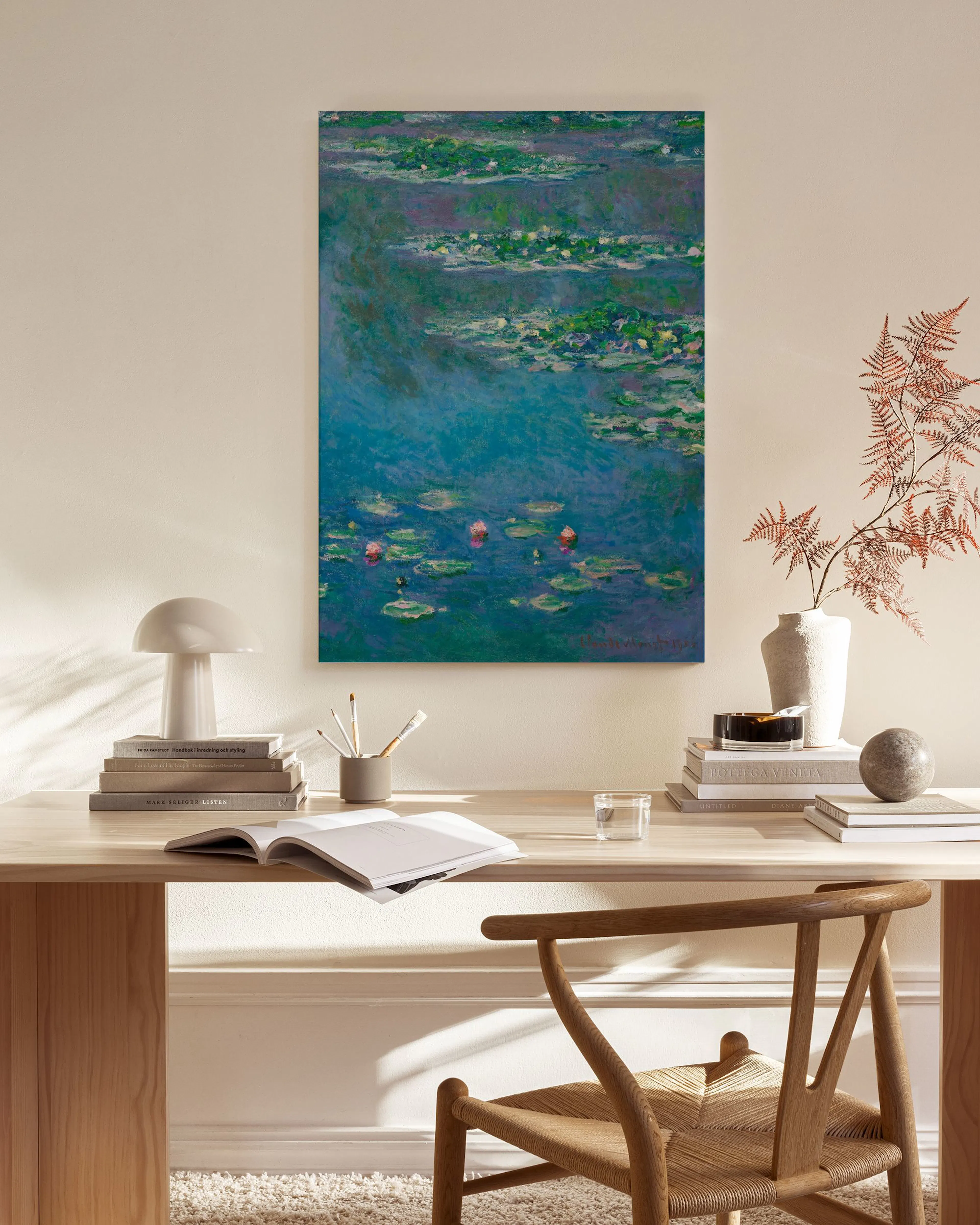Een canvas van Monets waterlelies in blauwgroene tinten, hangend boven een houten dressoir in een lichte woonkamer.