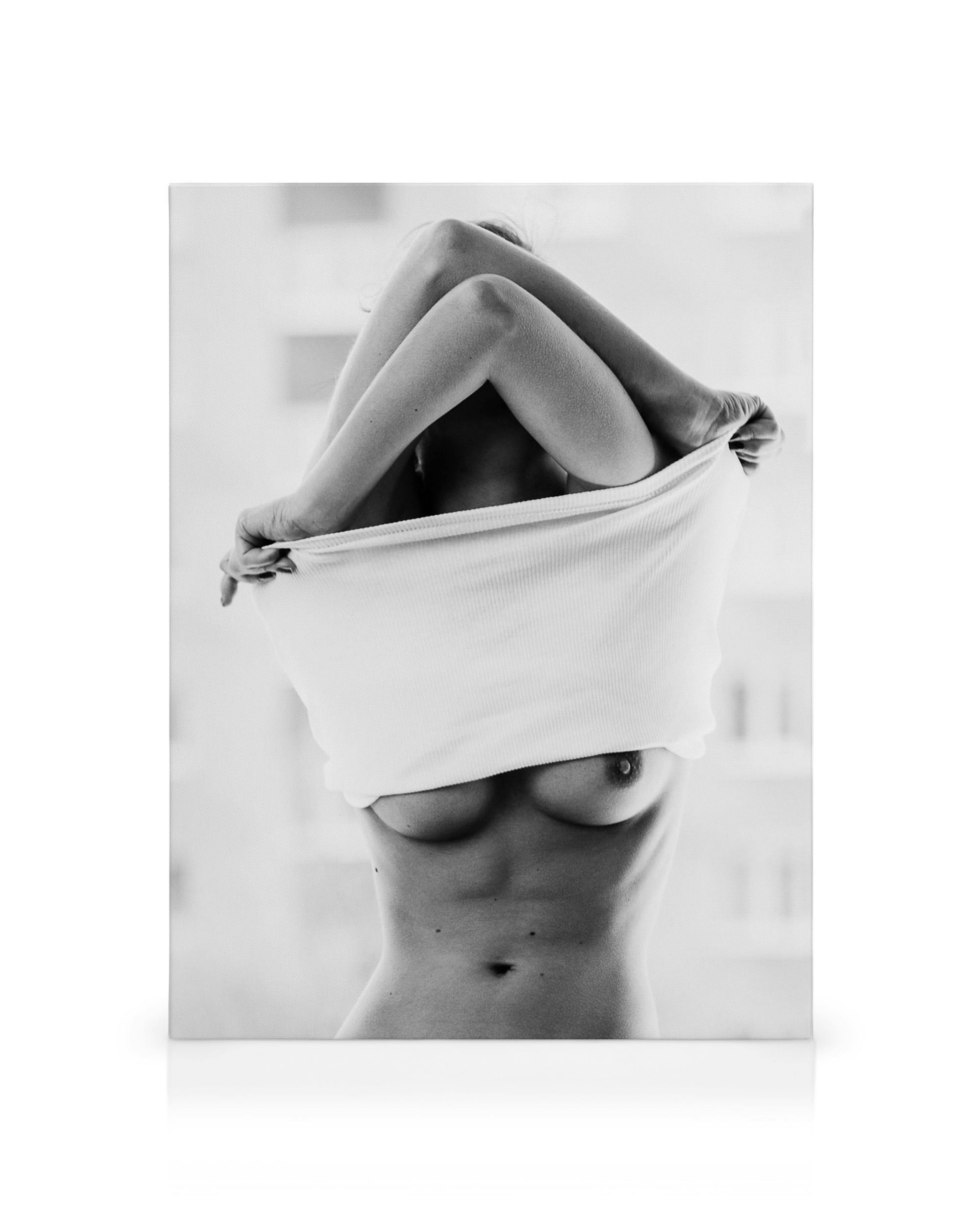 Black and white canvas print of a woman undressing, partially covering her face with arms and clothing.