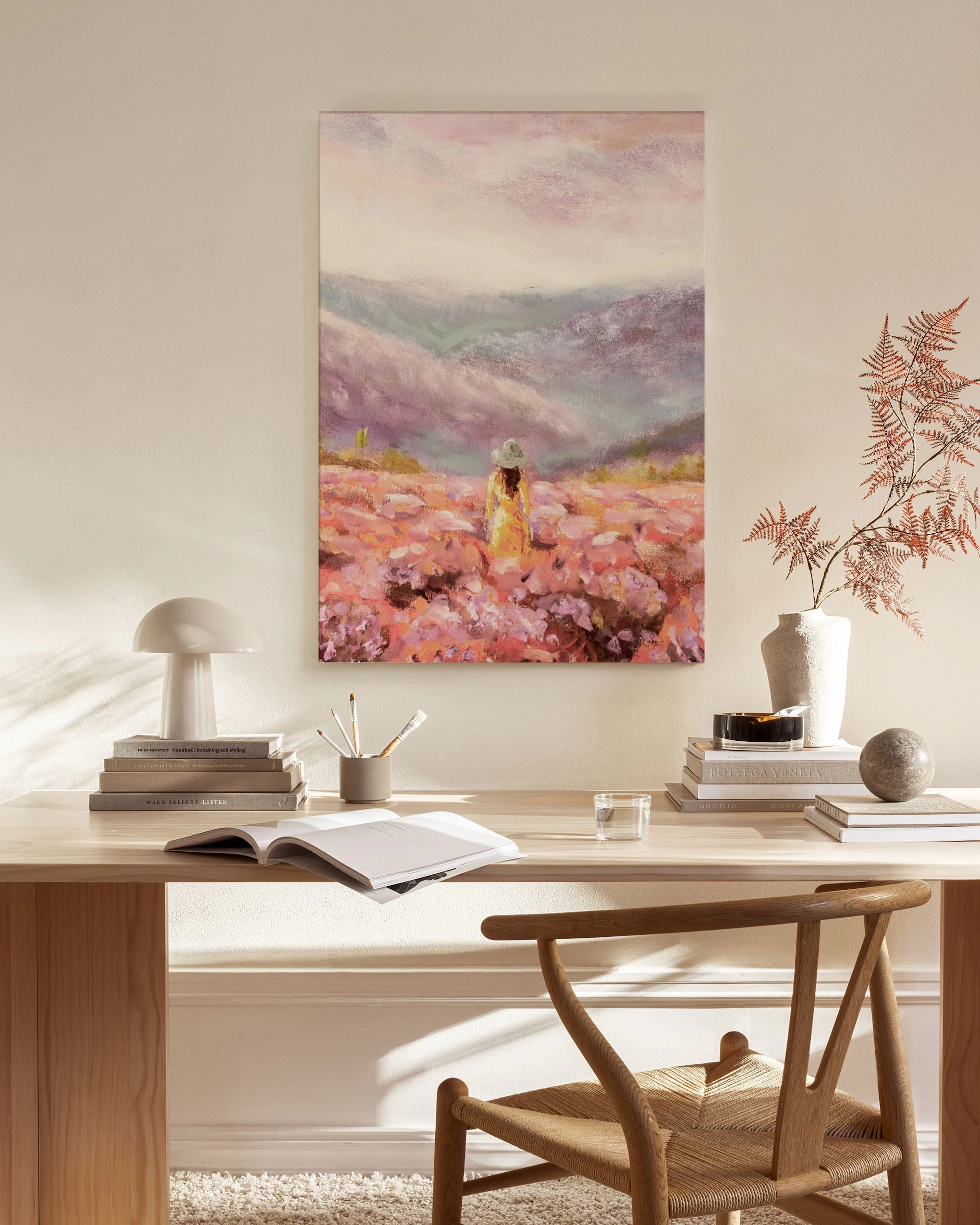 Canvas van een vrouw in een bloemenveld met paarse bergen, hangend in een neutrale woonkamer.