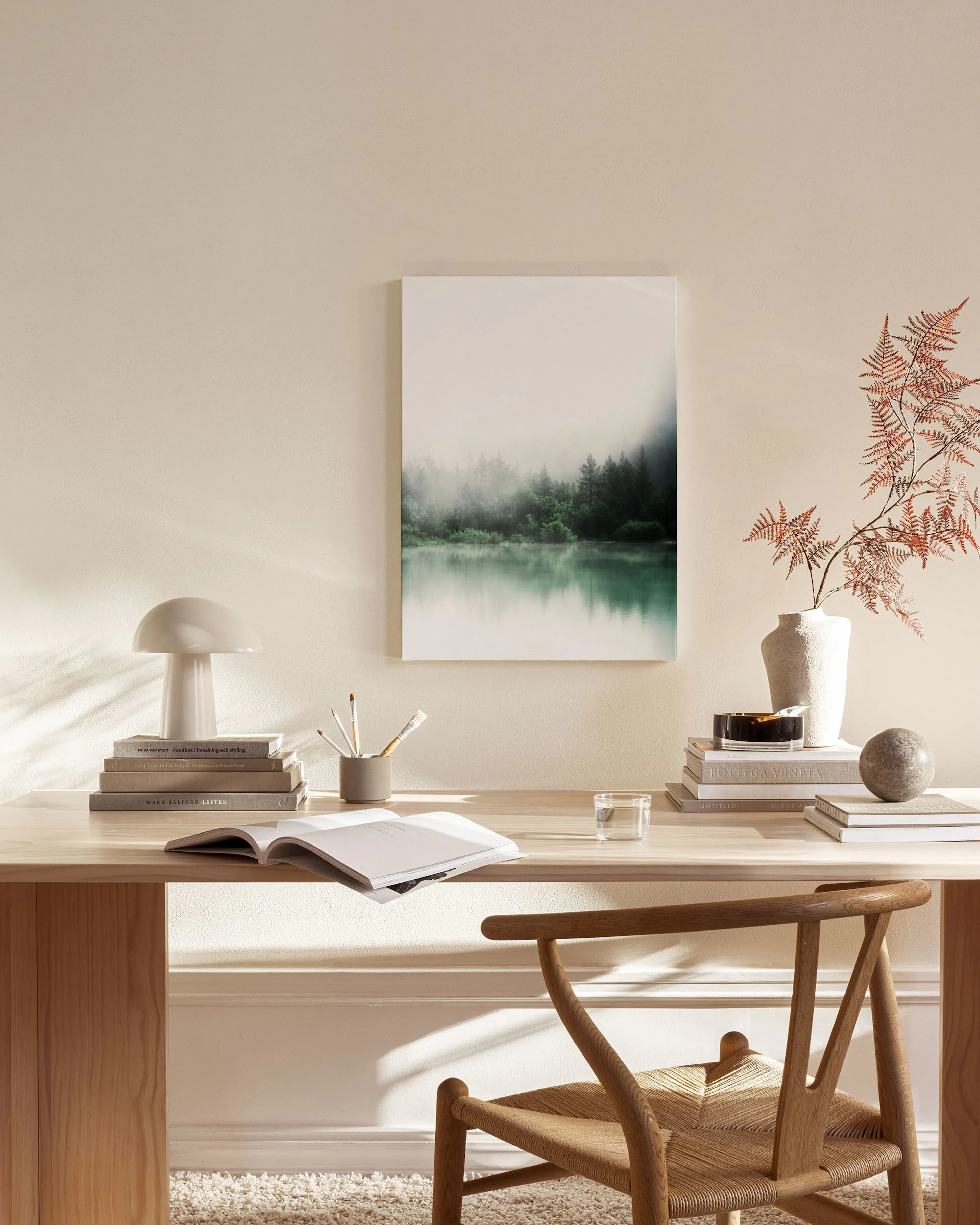 Canvas van een mistig bos met groene bomen en een spiegelend meer, hangend in een moderne woonkamer.