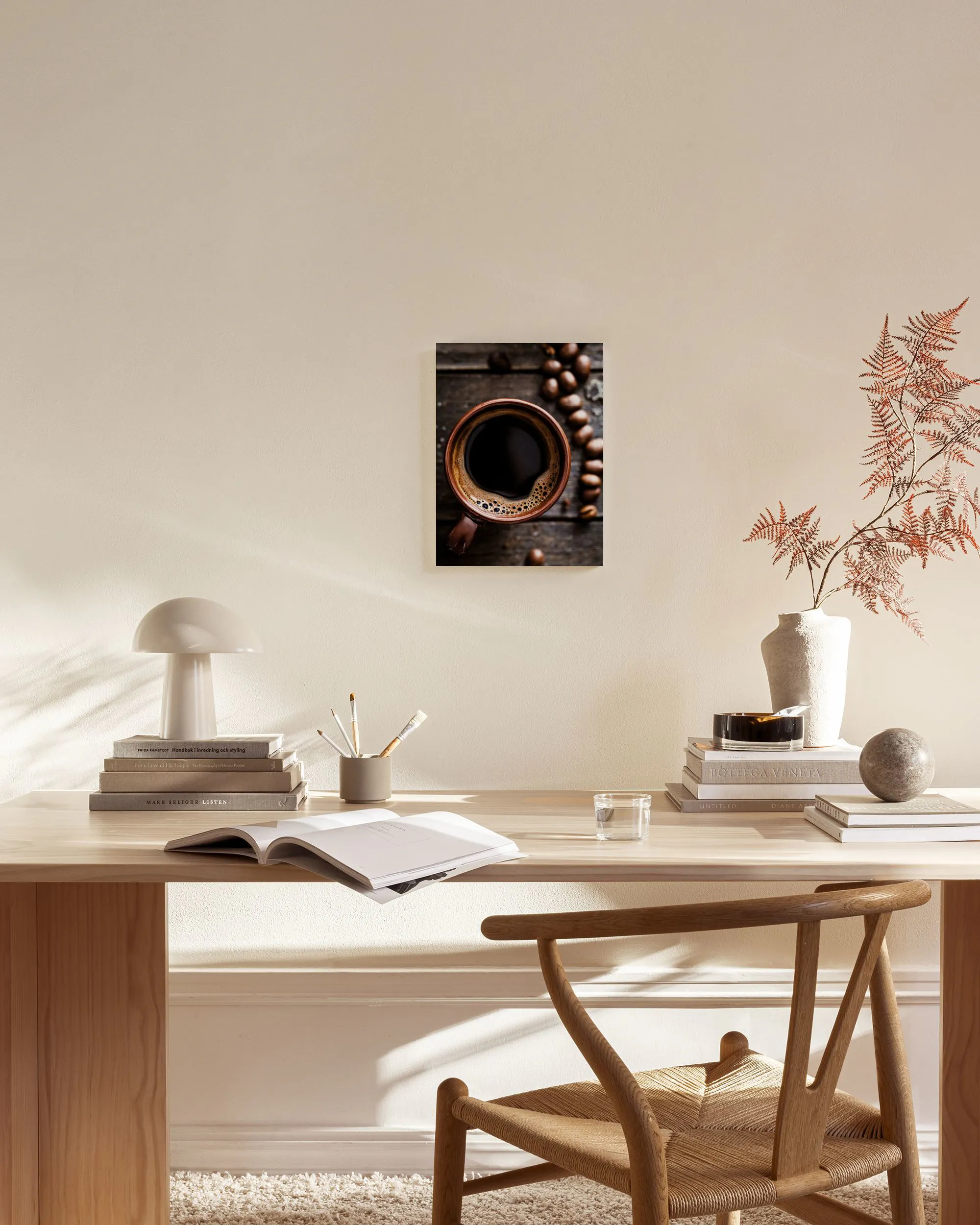 Tela decorativa com caneca de café quente e grãos de café, exposta numa sala de estar com mobiliário de madeira e tons neutros.
