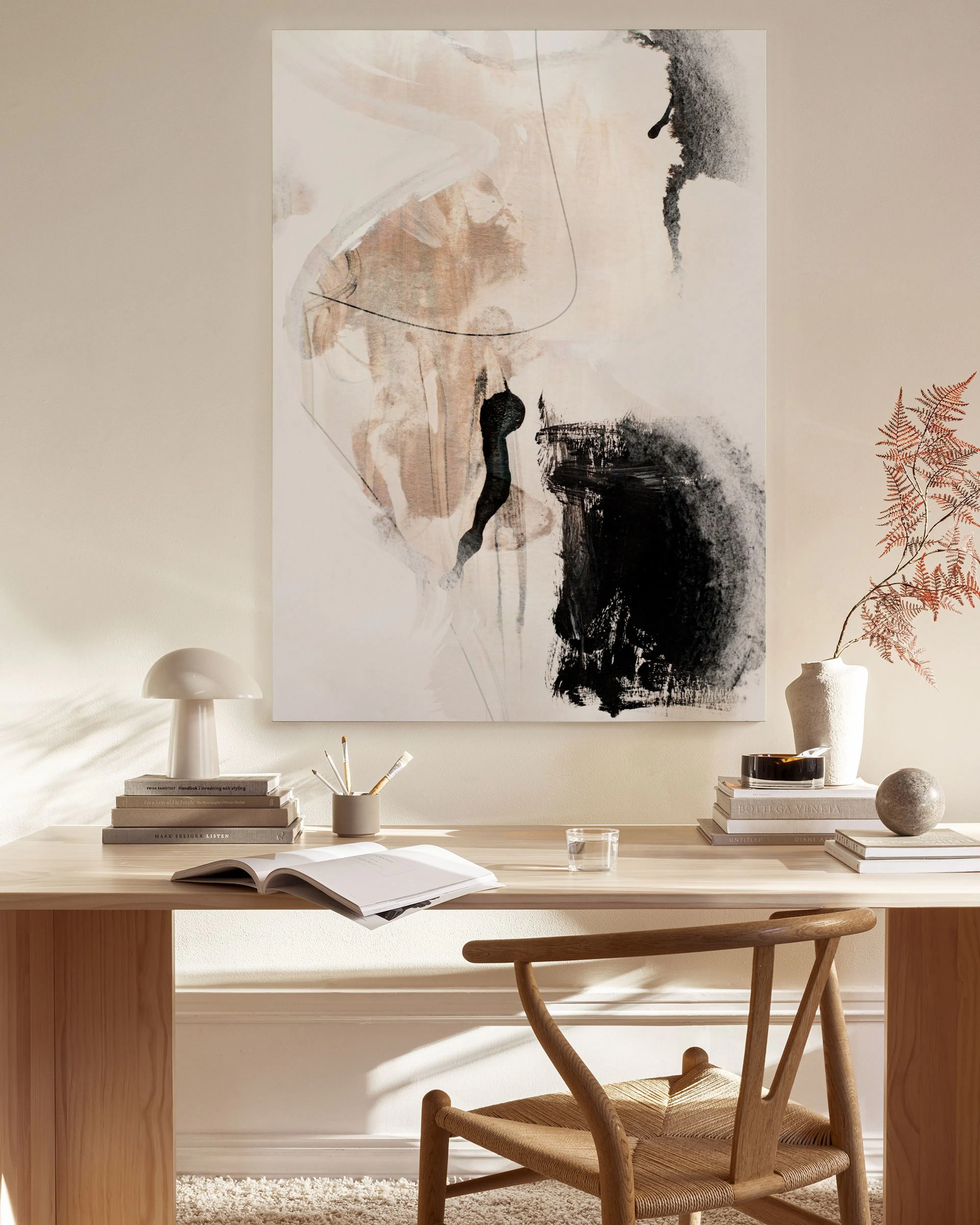 Abstract canvas print with black, beige, and white brushstrokes, hanging in a minimalist living room above a wooden console.