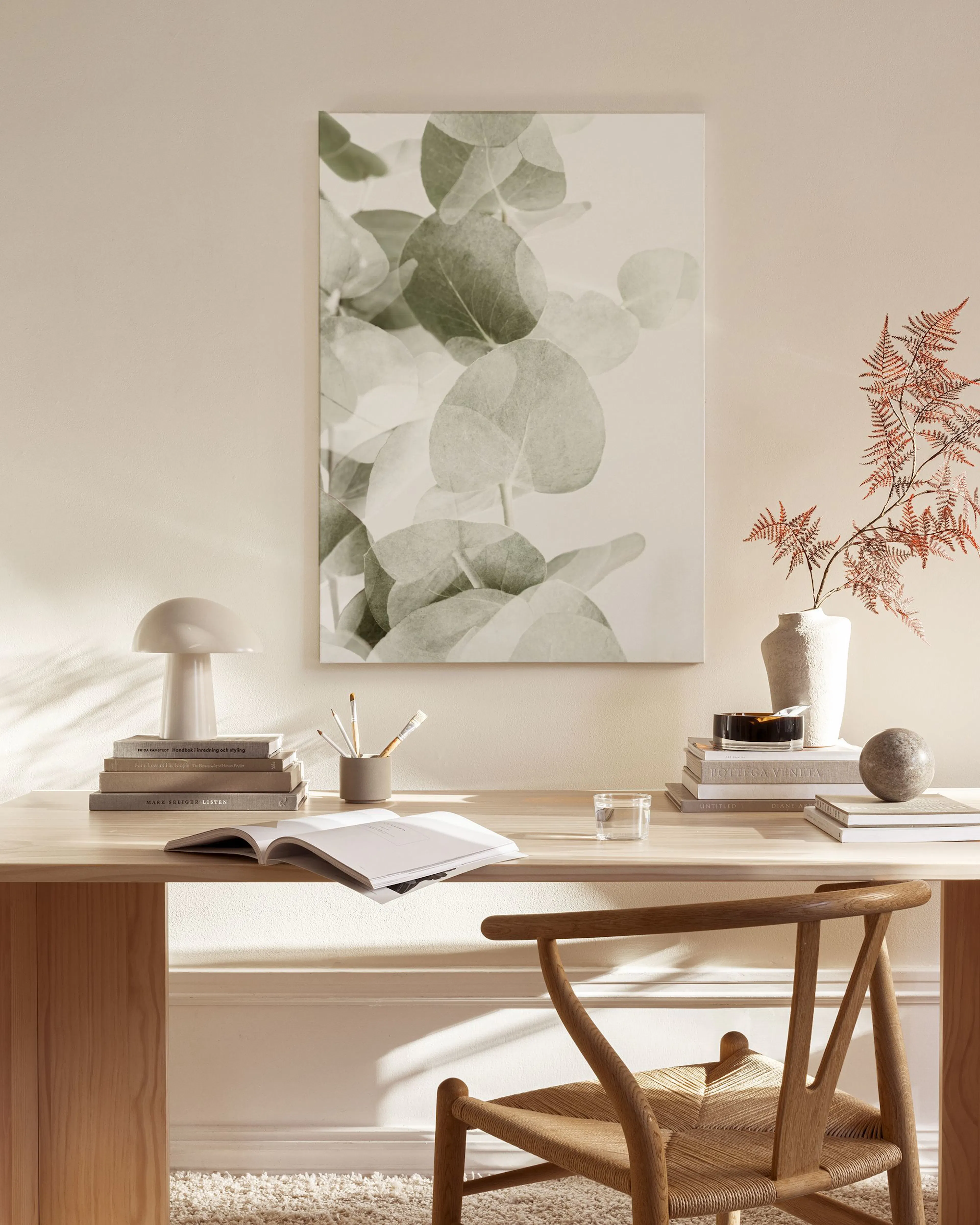 Leinwandbild mit Eukalyptusblättern in Grüntönen, minimalistisch über einem Lowboard im Wohnzimmer hängend.