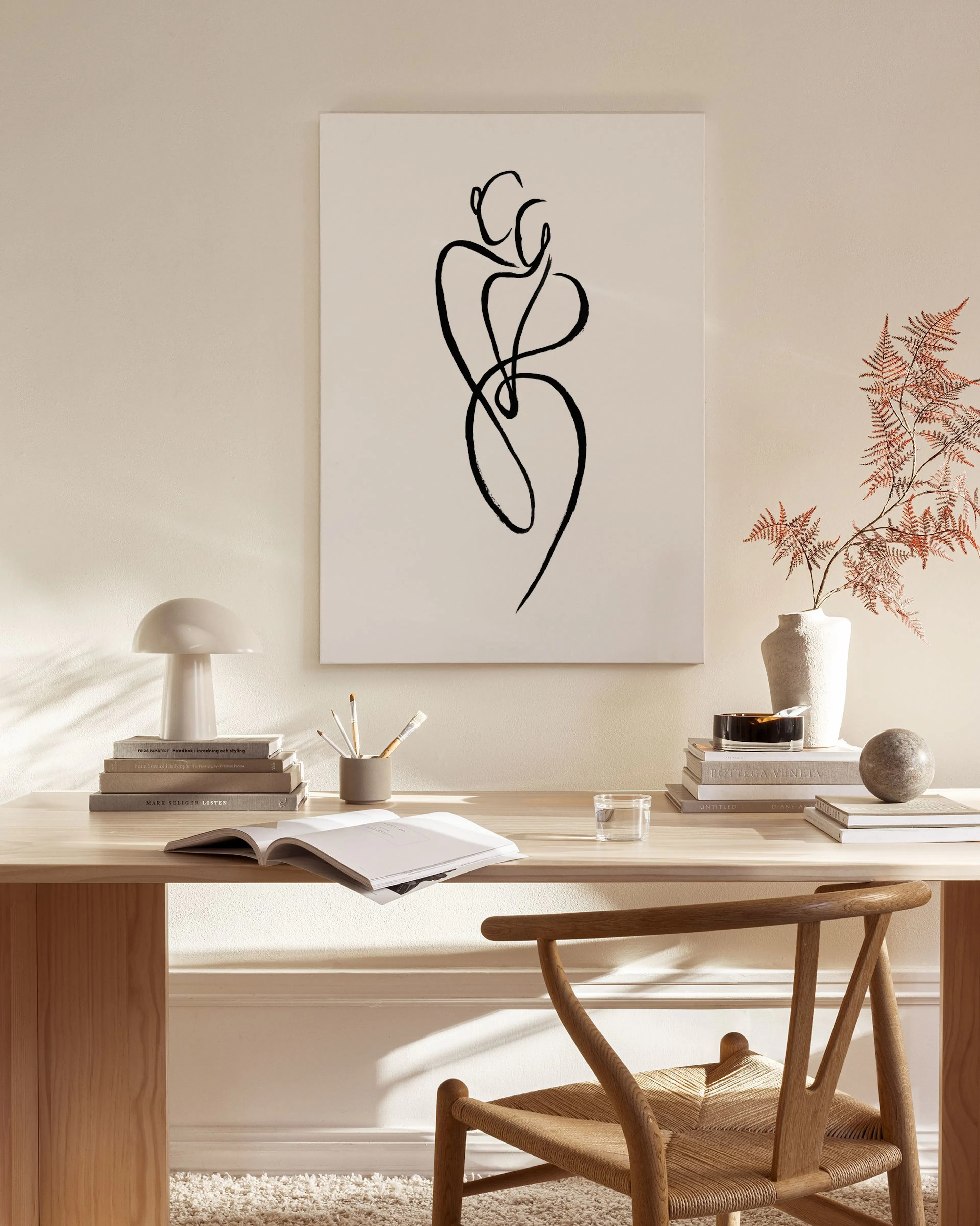 Leinwandbild mit schwarzer Linienzeichnung von zwei umarmenden Personen in einem hellen Wohnzimmer über einem Sideboard.