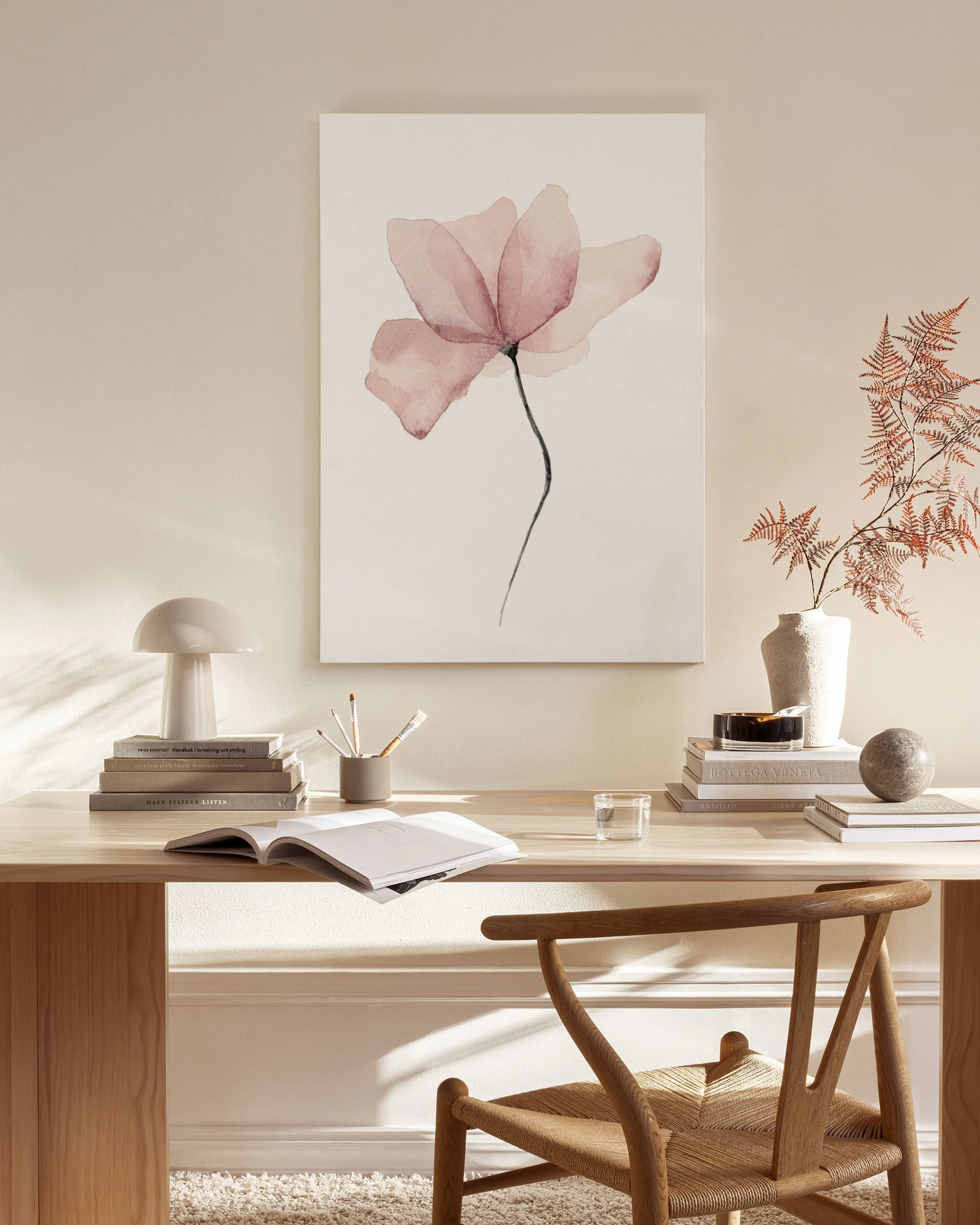 Stampa su tela con fiore rosa trasparente su sfondo bianco, appesa in un soggiorno moderno.