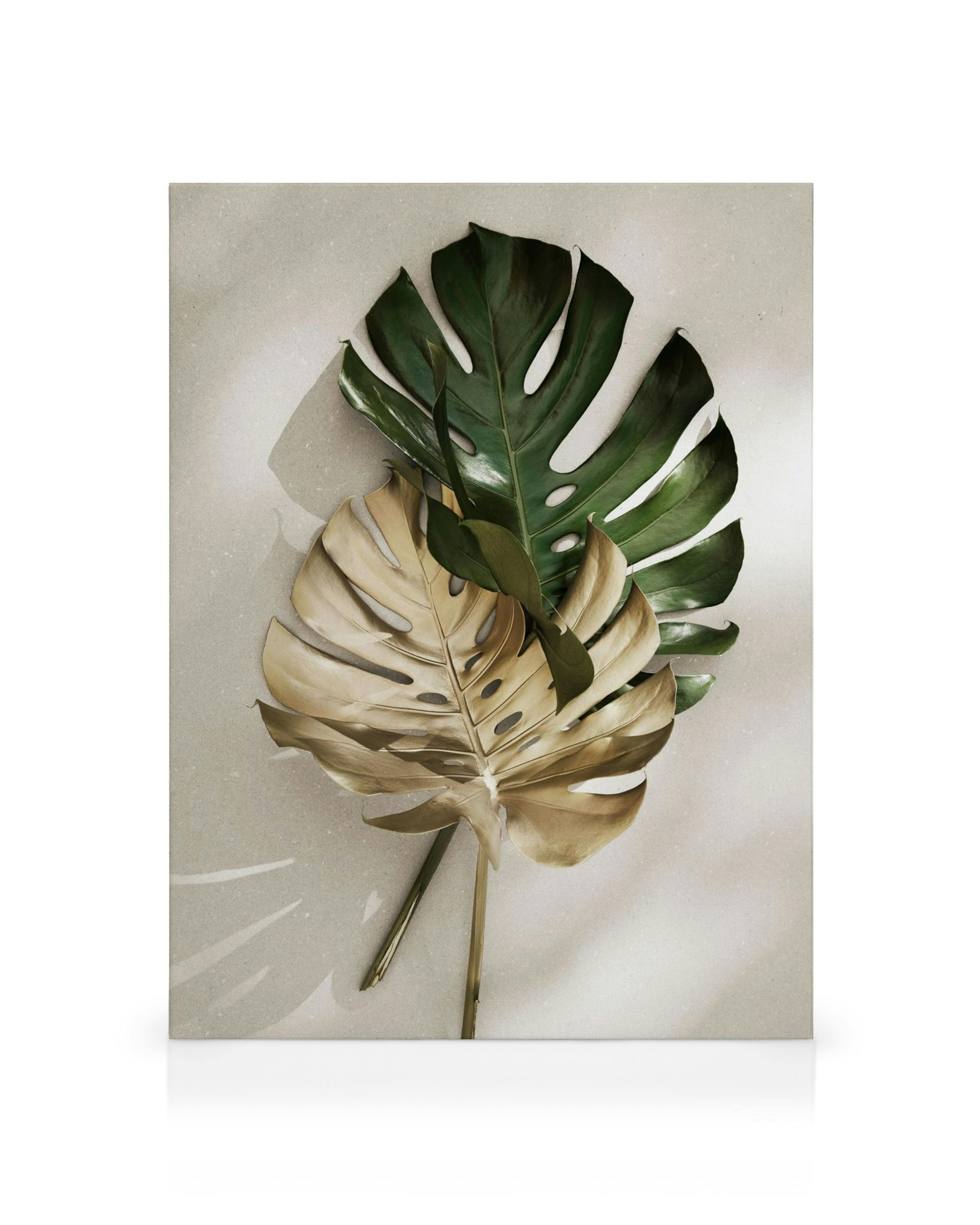 Botanical canvas print with a green monstera leaf overlapping a gold monstera leaf on a beige background.