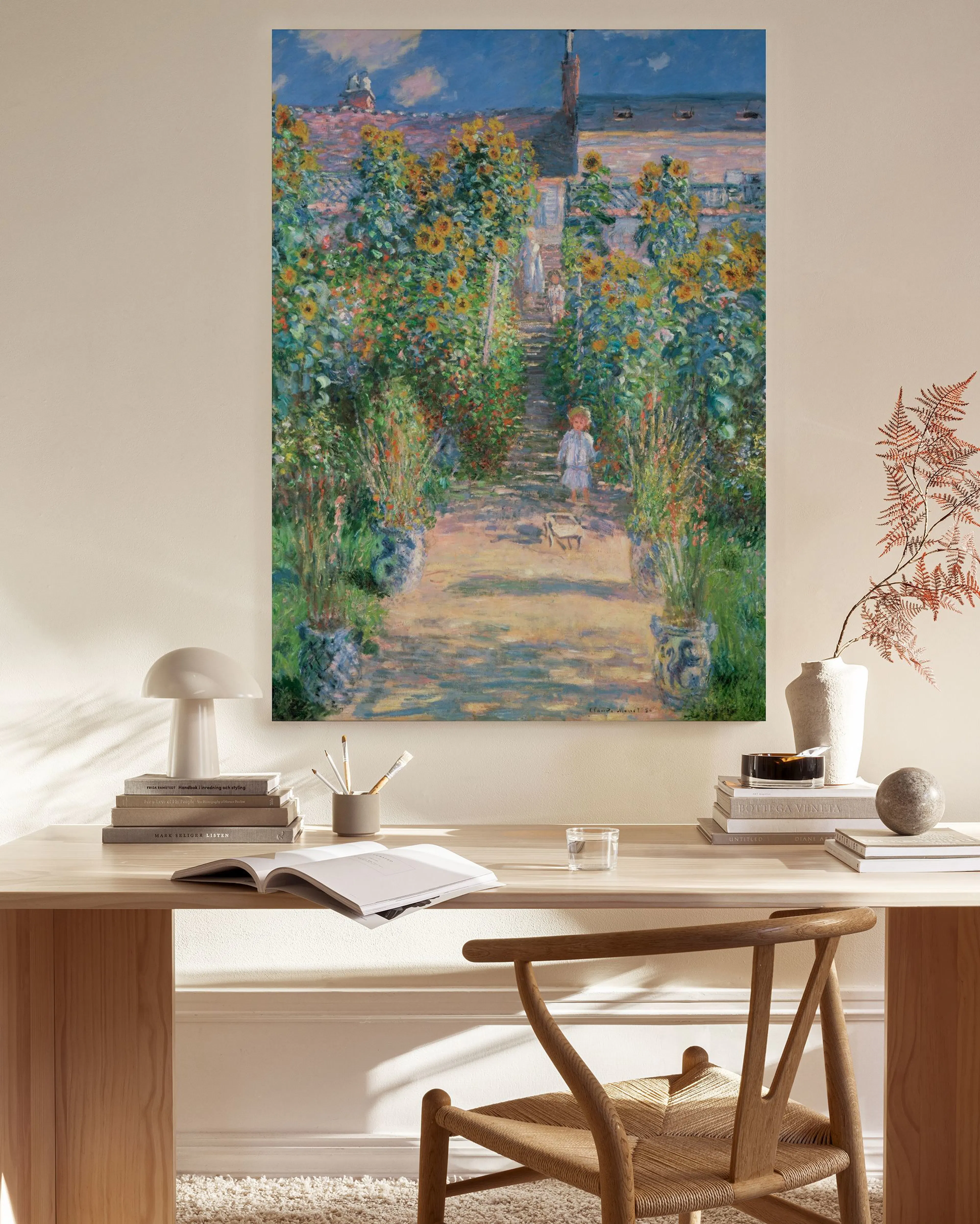Lærred med Monets havemaleri i et lyst, moderne rum med træmøbler og en hvid lampe.