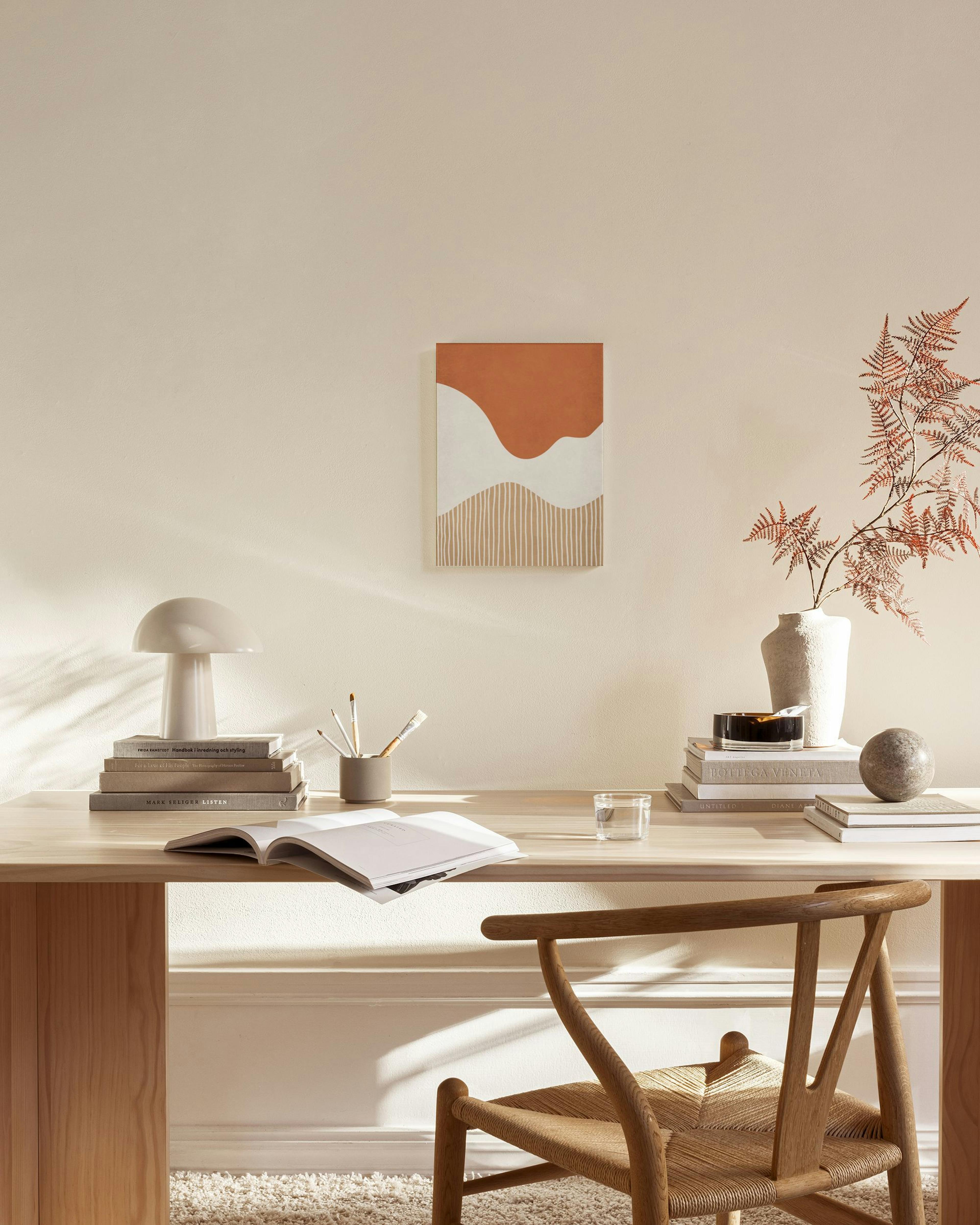 Tela decorativa com formas abstratas em terracota e branco, com linhas verticais na parte inferior, disposta num ambiente de sal