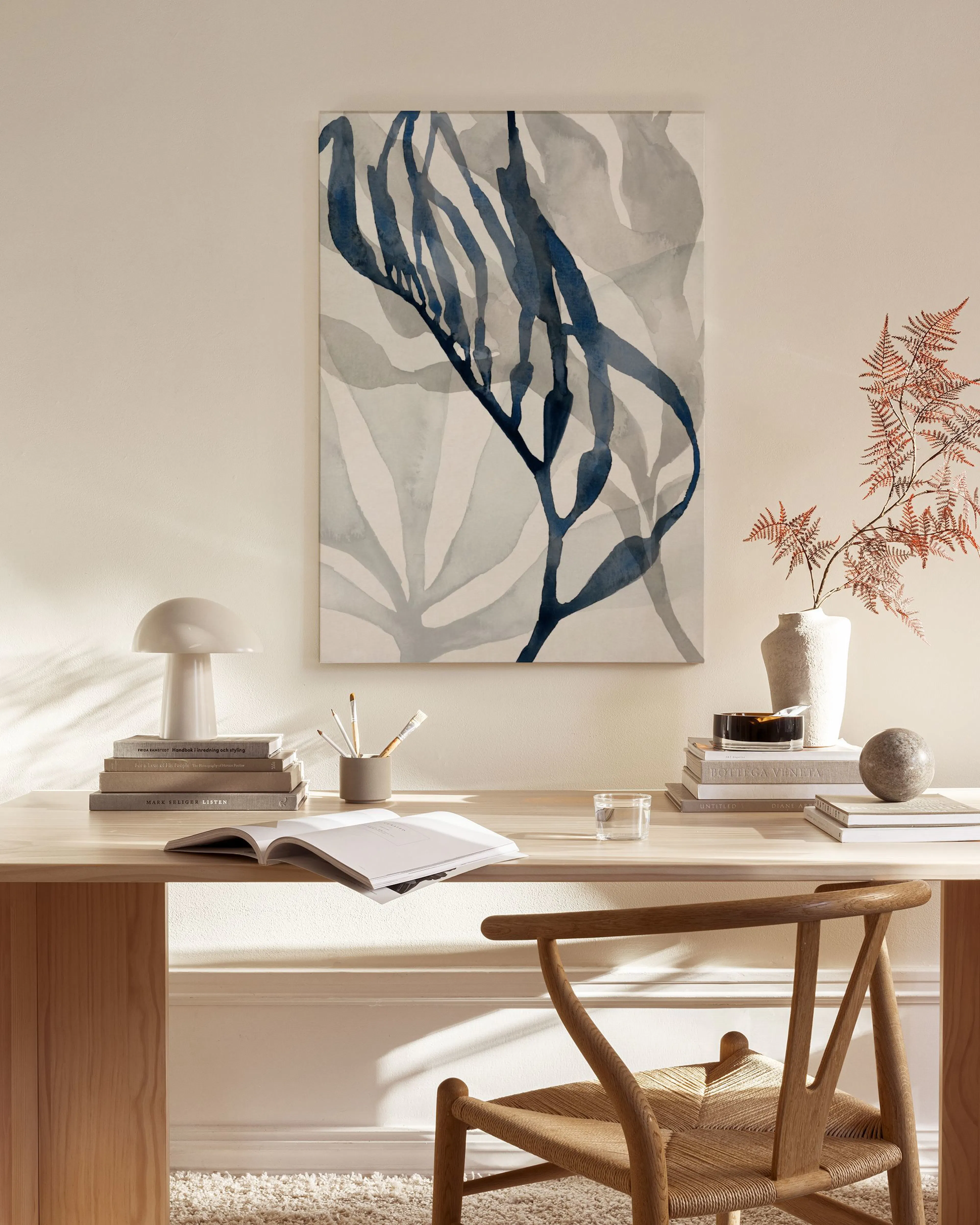 Toile de varech bleu sur fond clair, suspendue dans un salon moderne au-dessus d’un meuble bas en bois.